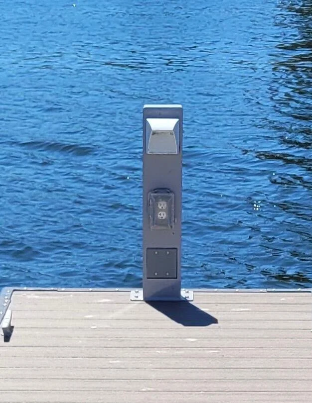 Electric vehicle charging station on a dock overlooking a body of water.