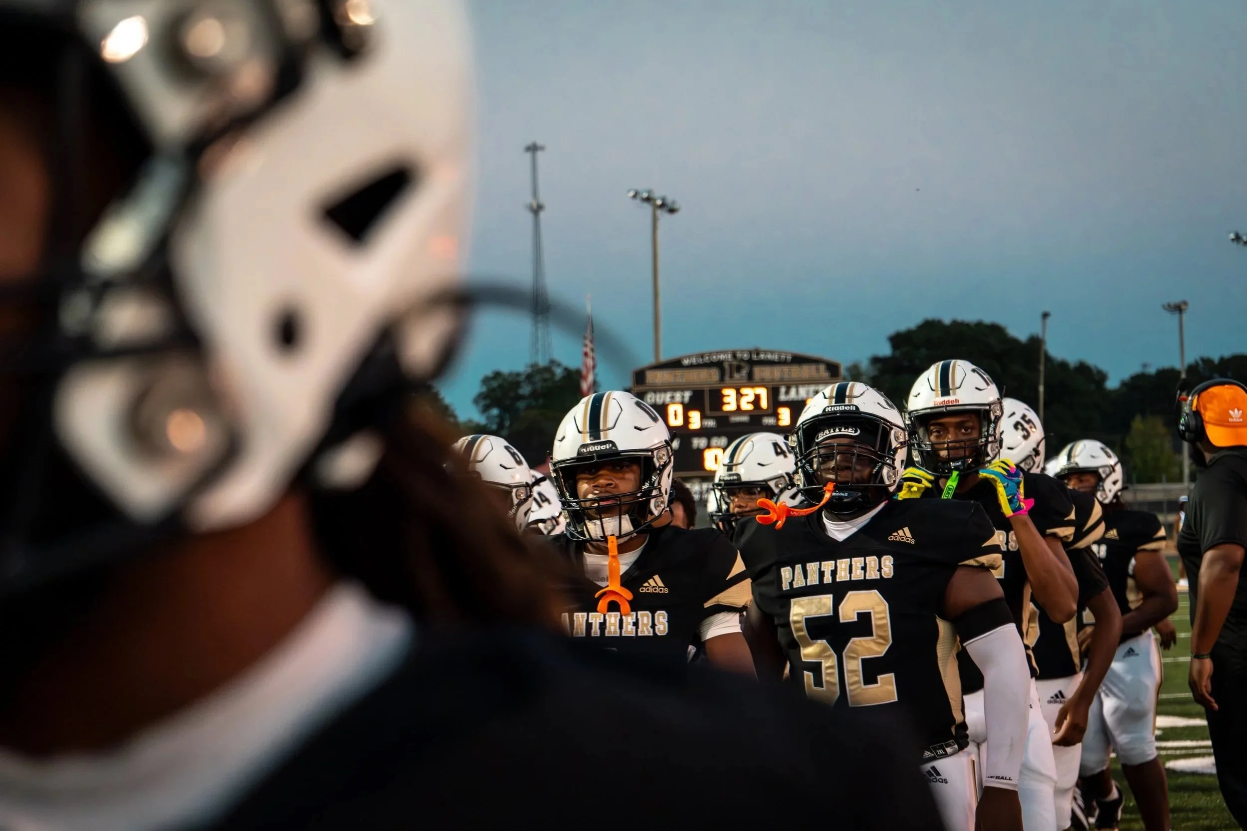 High school football team called the Panthers gathered on the field during dusk.