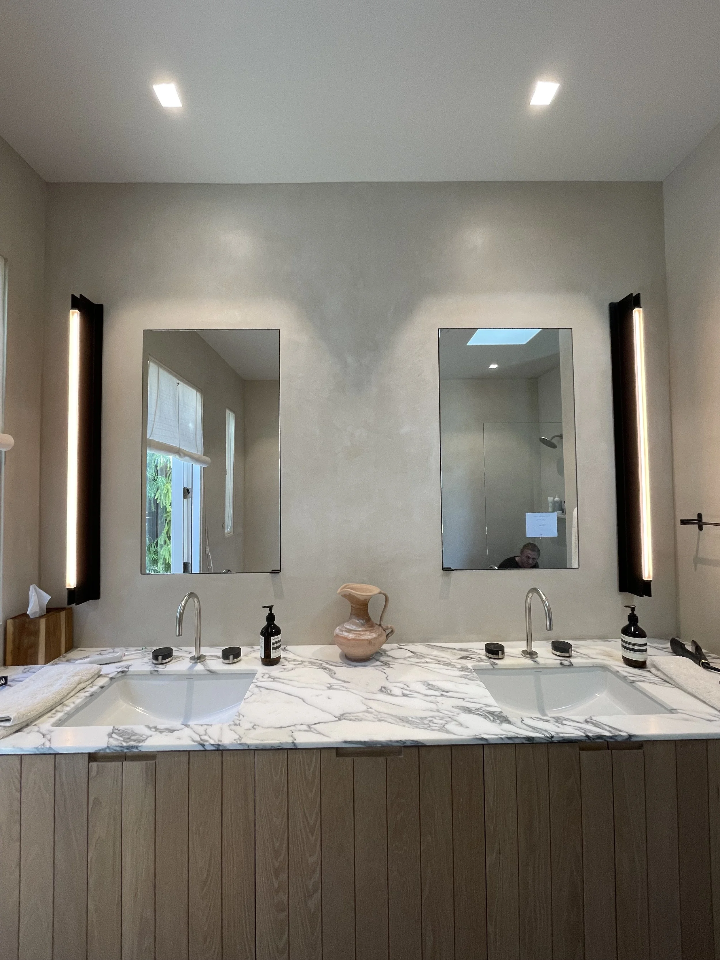 Microcement bathroom vanity with two sinks, a marble countertop, and two mirrors.