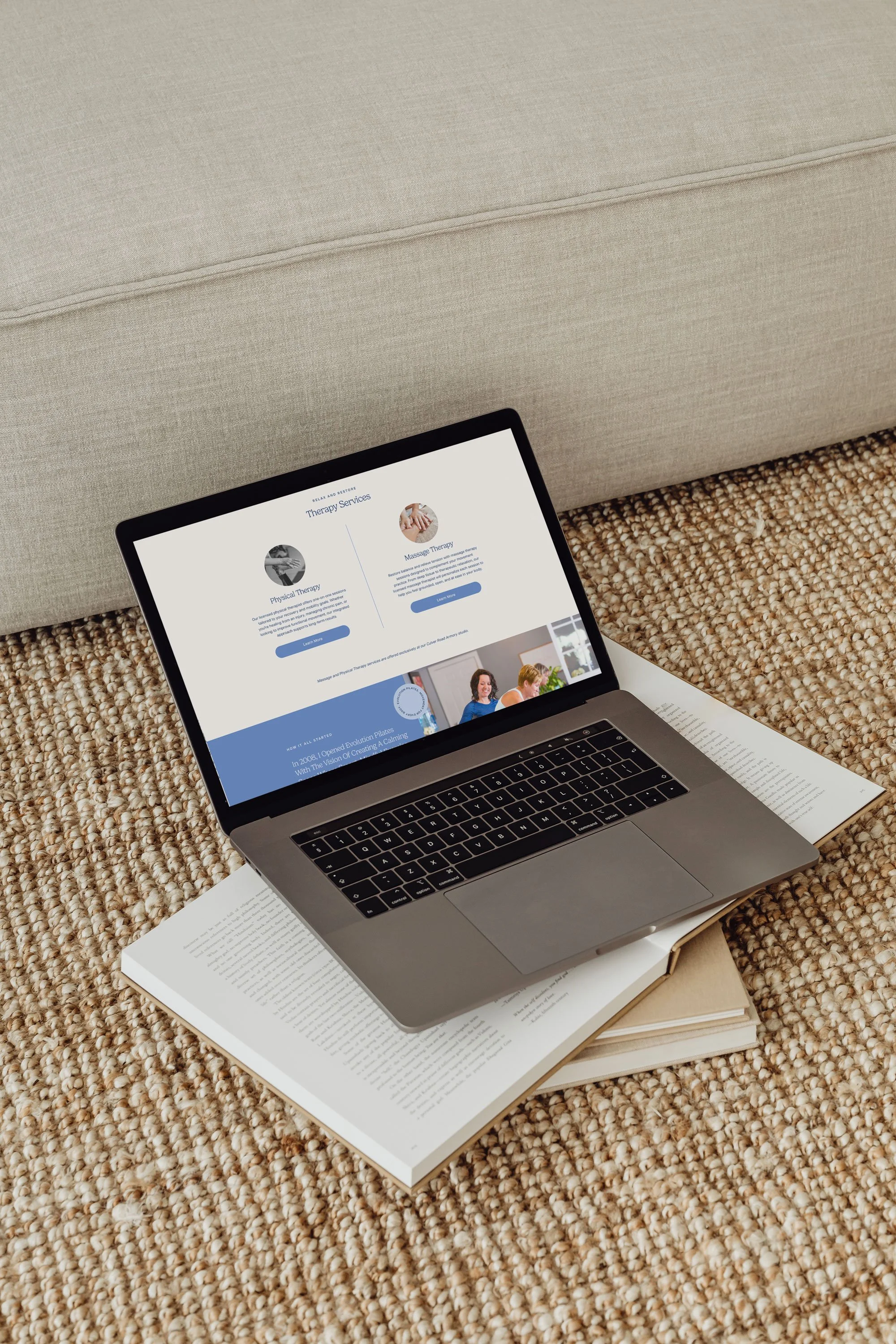 Open laptop on open book on carpet, displaying therapy services webpage.