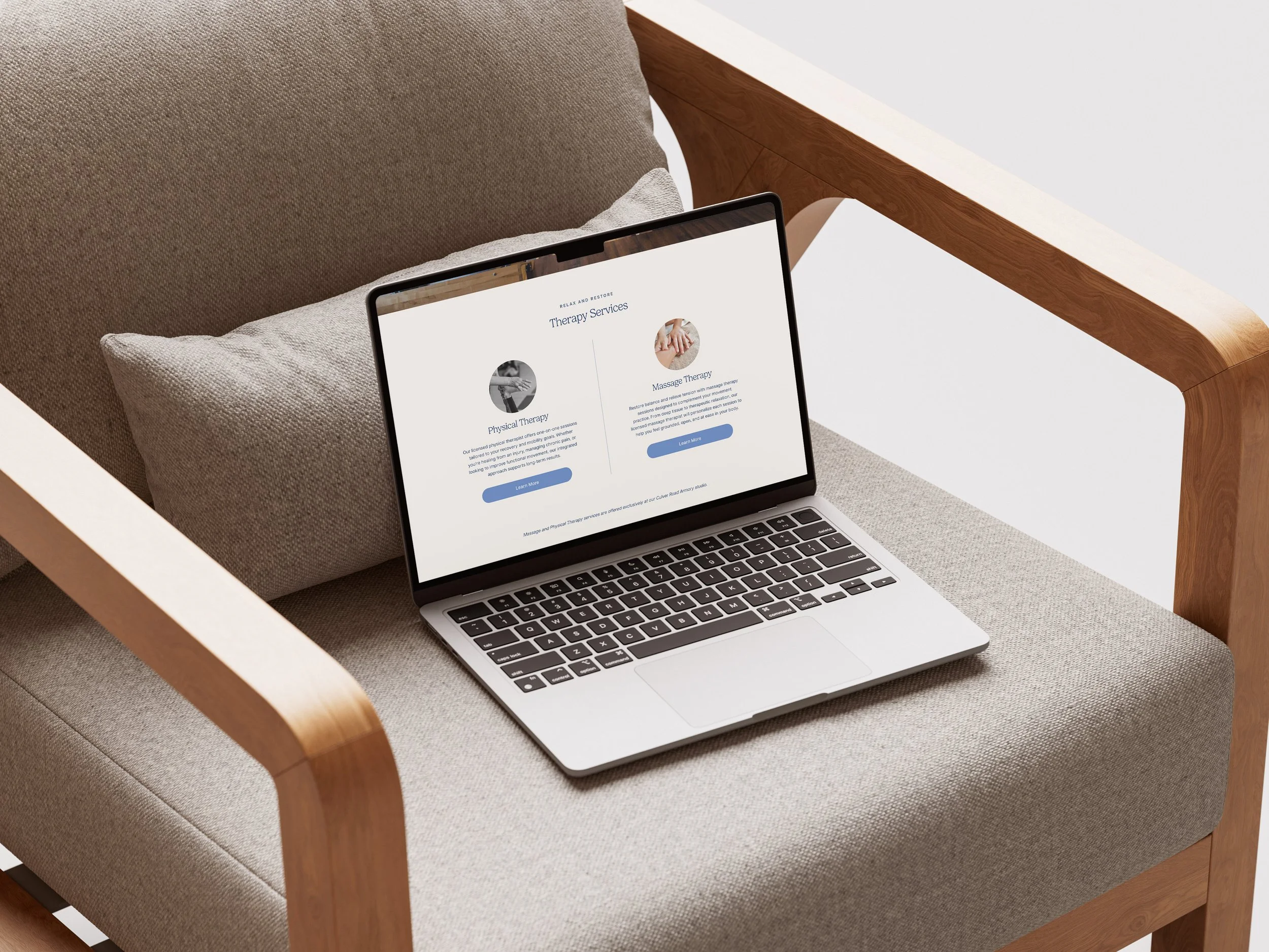A laptop displaying a therapy services webpage on a beige armchair with wooden armrests, next to a gray pillow.