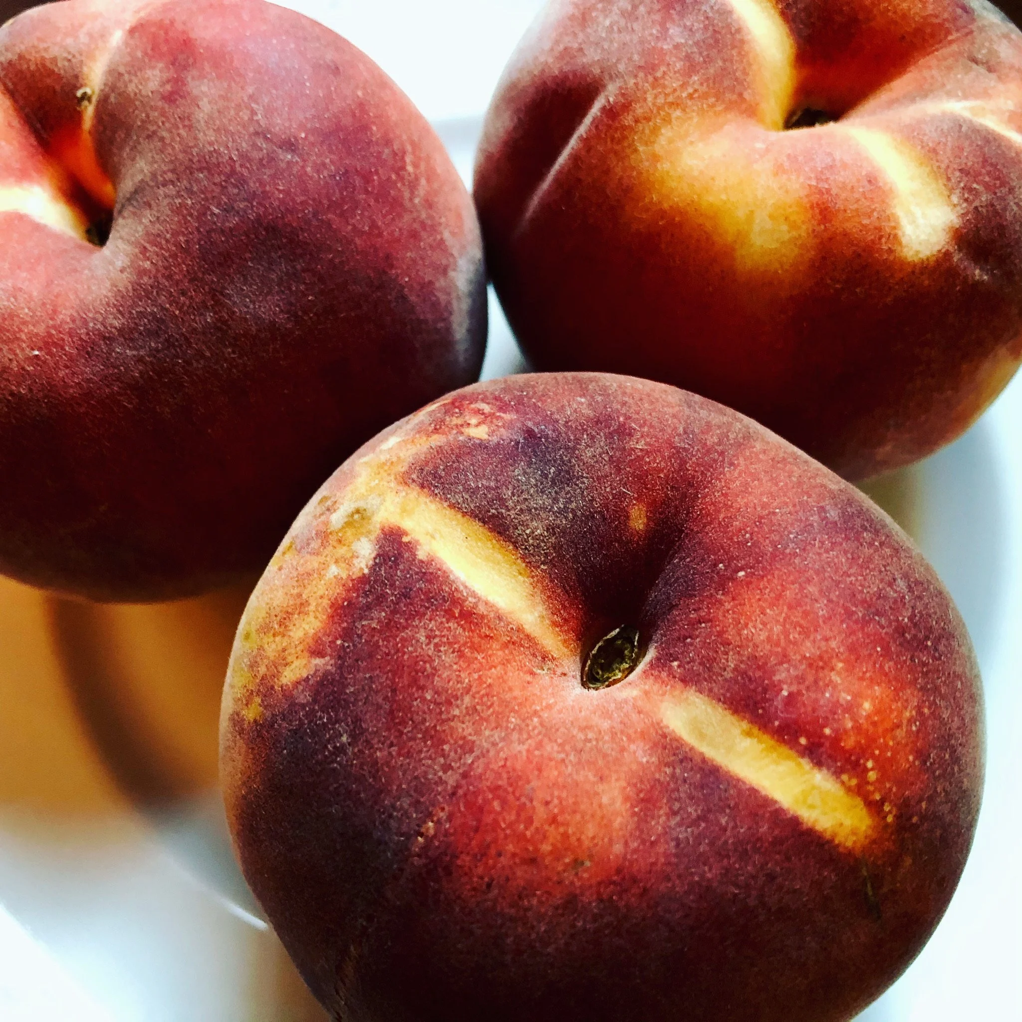Close-up of three peaches on a white surface
