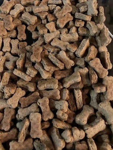 Close-up of dry, small, irregularly shaped brown dog kibble pieces.