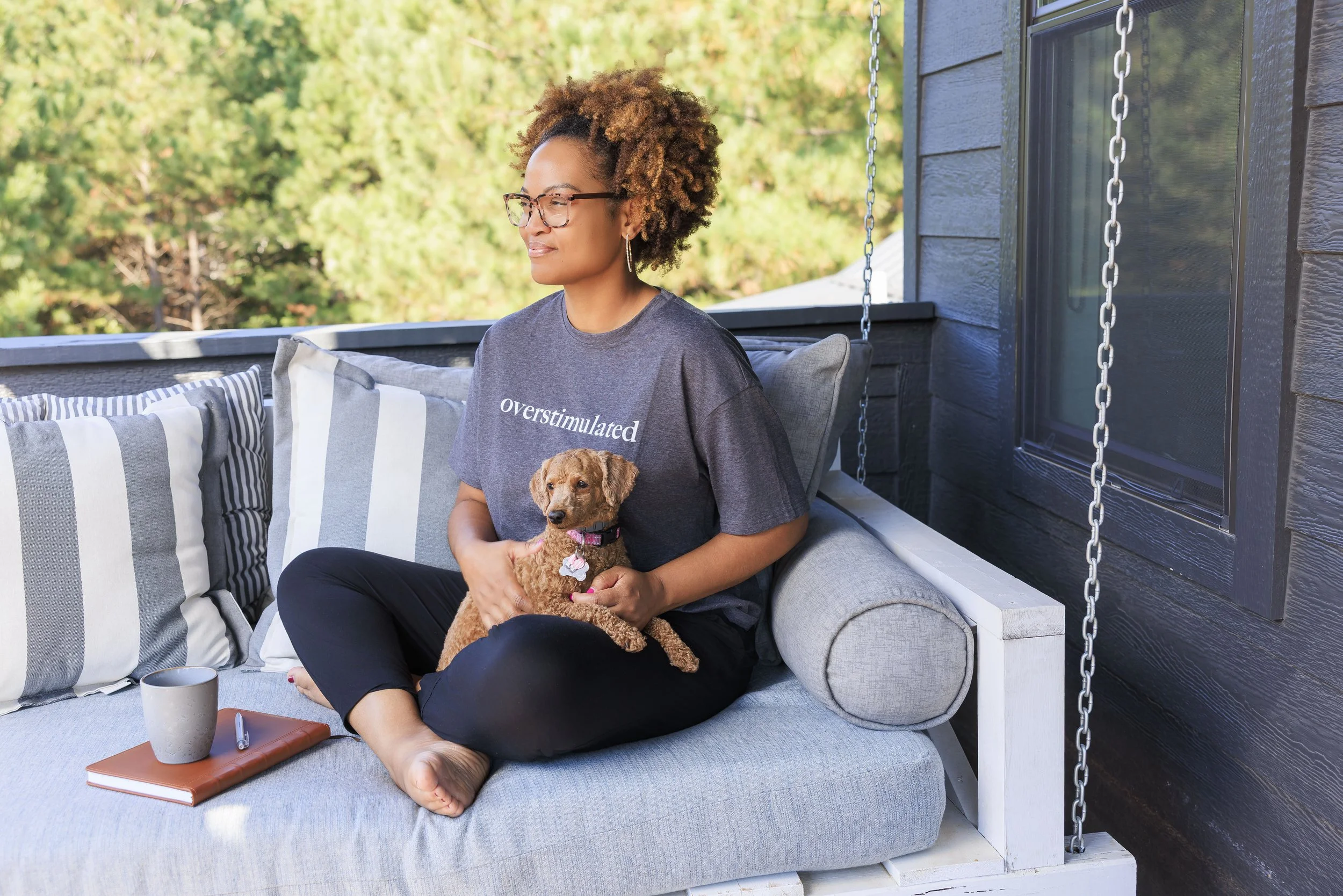 Keisha Gaddis sitting on a porch swing holding a small brown dog.