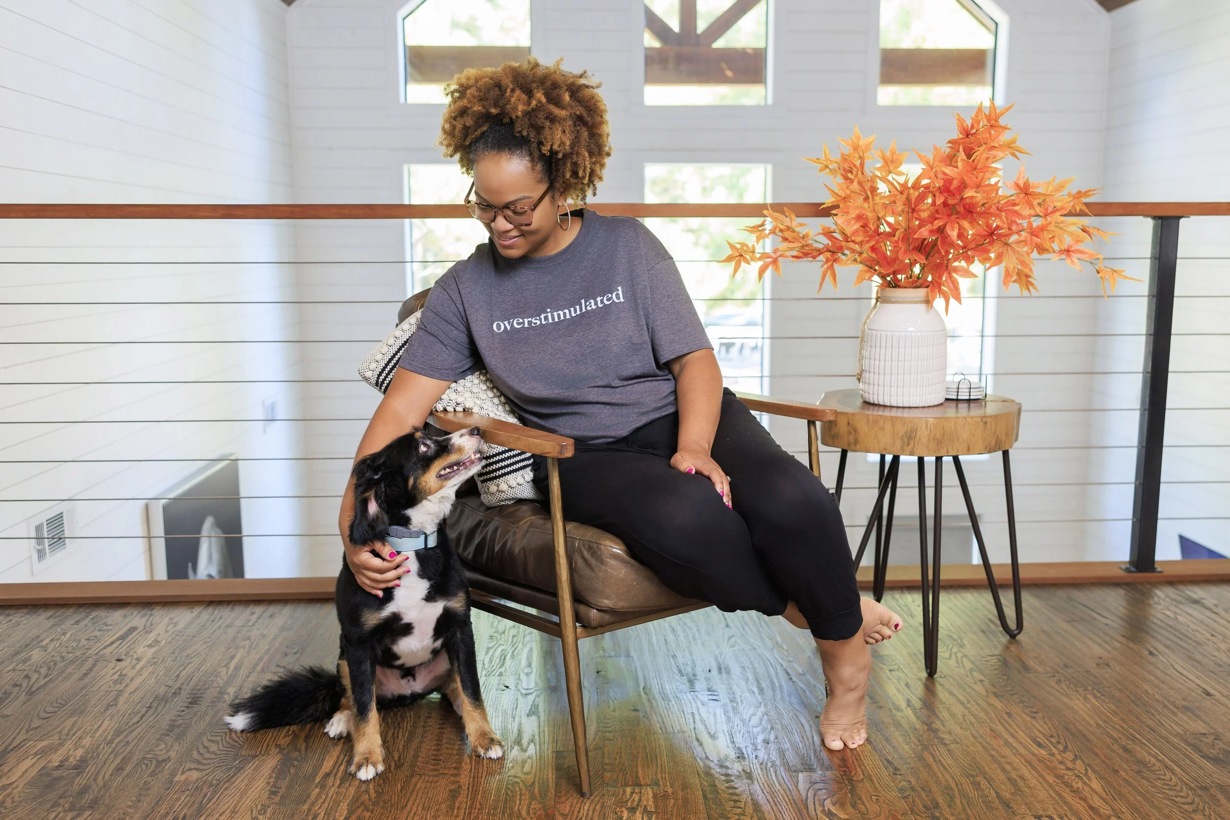 Keisha Gaddis sitting in a wooden chair, smiling while petting a dog.