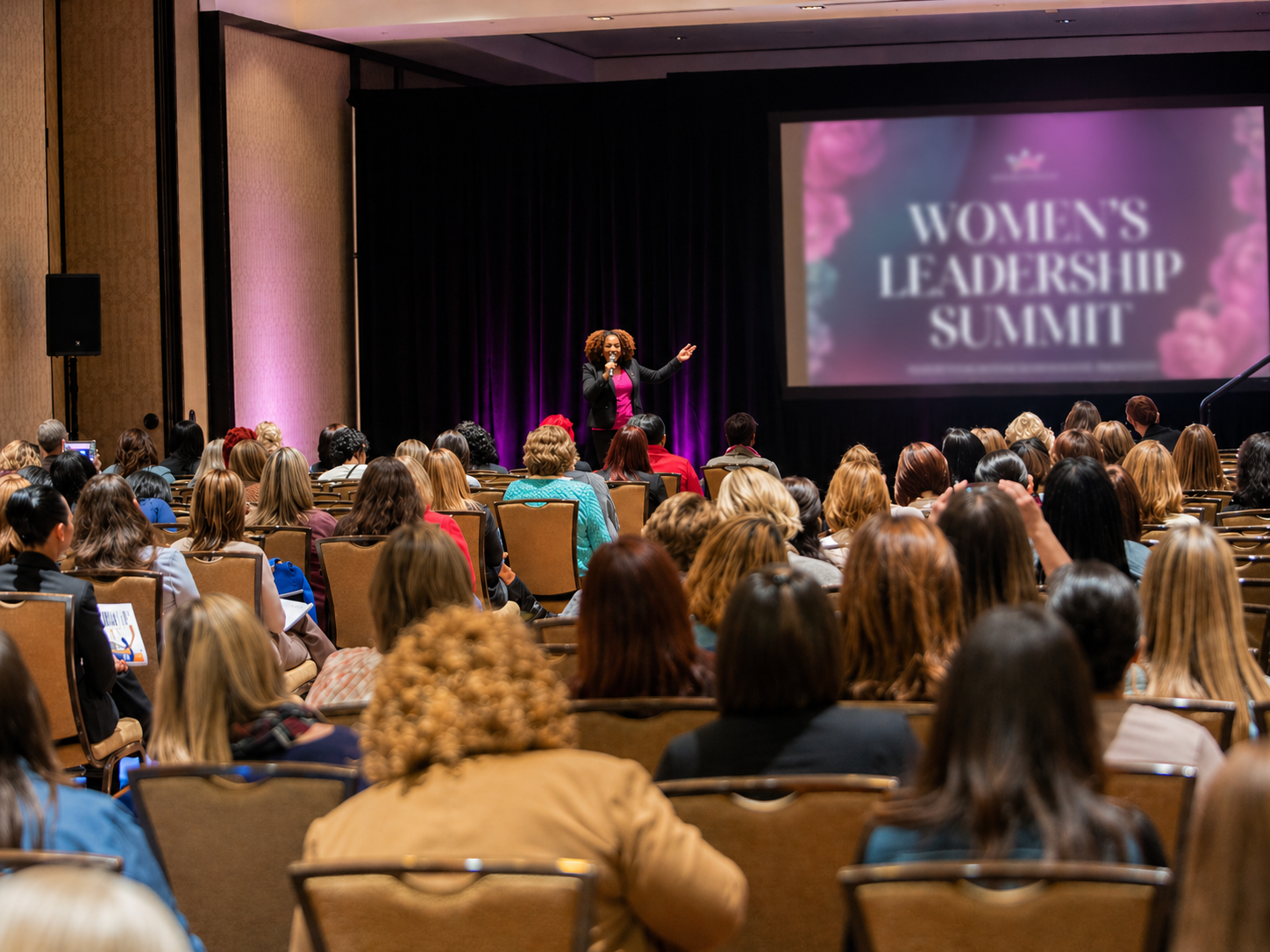Keisha Gaddis speaking on stage at a Women's Leadership Summit.
