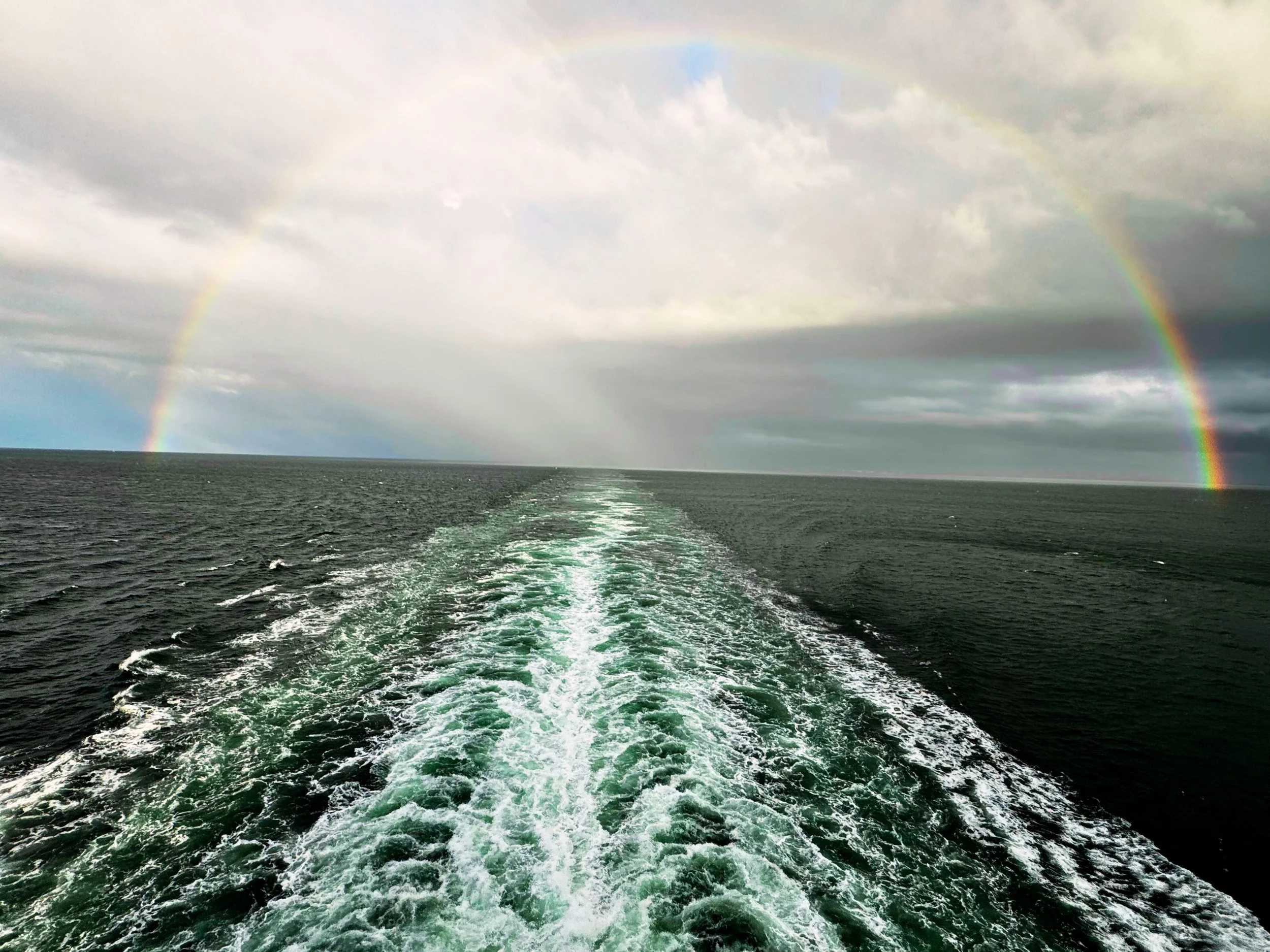 Rainbow arching over the water near the Tampa Bay Bridge — symbol of clarity, promise, and calm leadership from Wallace Impact Partners.