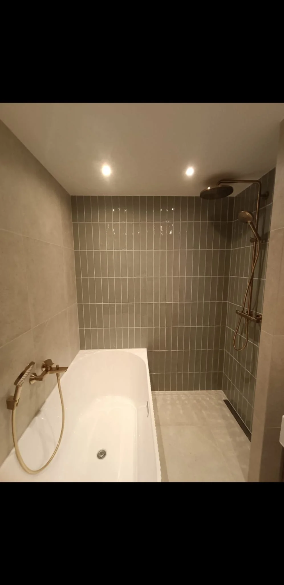 Bathroom with a bathtub on the left and a walk-in shower on the right, tiled walls, and ceiling lights.