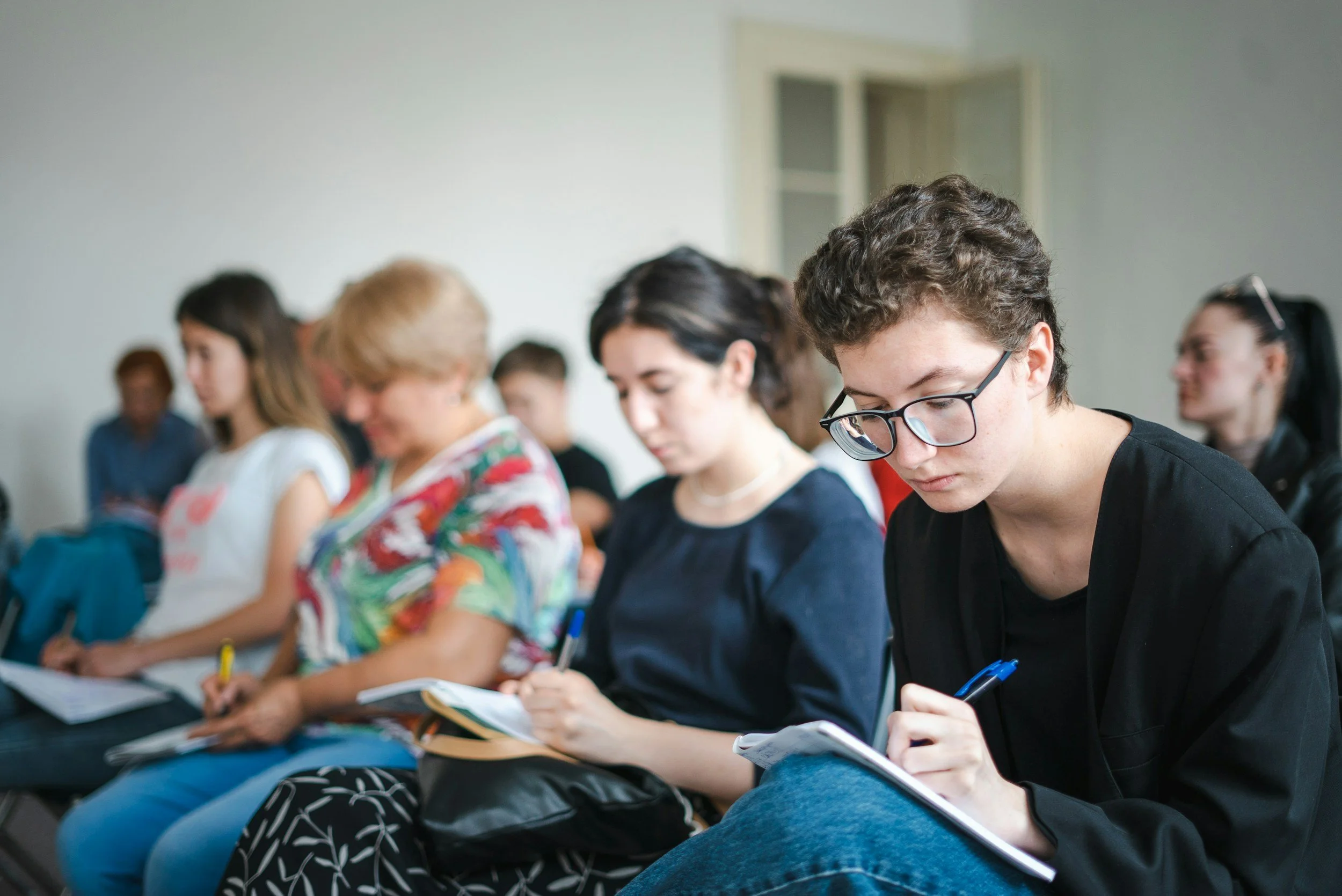 A group of diverse professionals receiving training, taking notes attentively.
