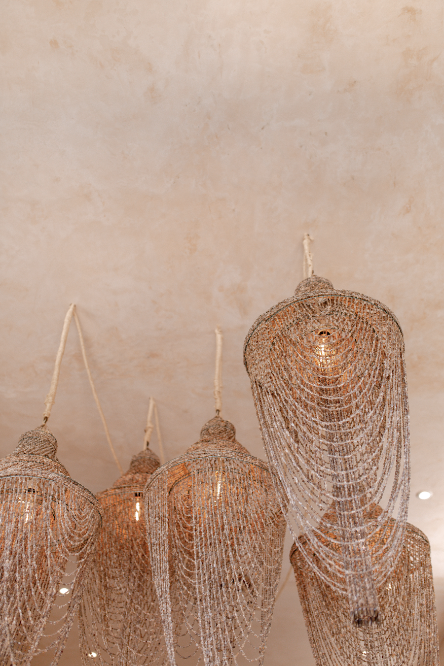 Elegant chandelier with multiple layered metal and crystal chains hanging from a cream-colored ceiling.