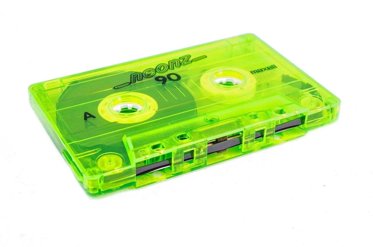 A neon green Maxell cassette tape with transparent case and visible magnetic tape inside.