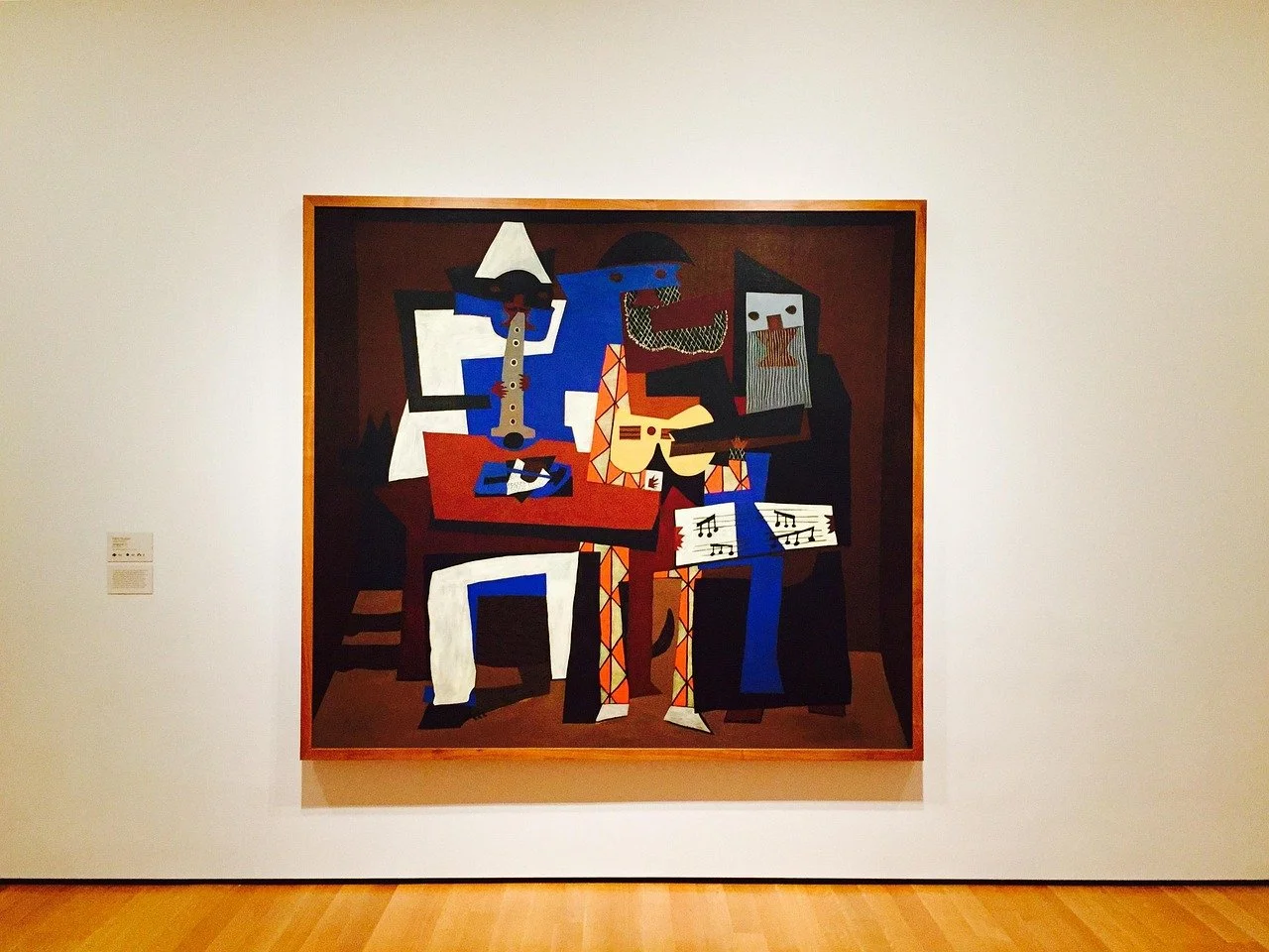 Cubist-style painting of three musicians playing instruments, hung on a white wall in an art gallery.