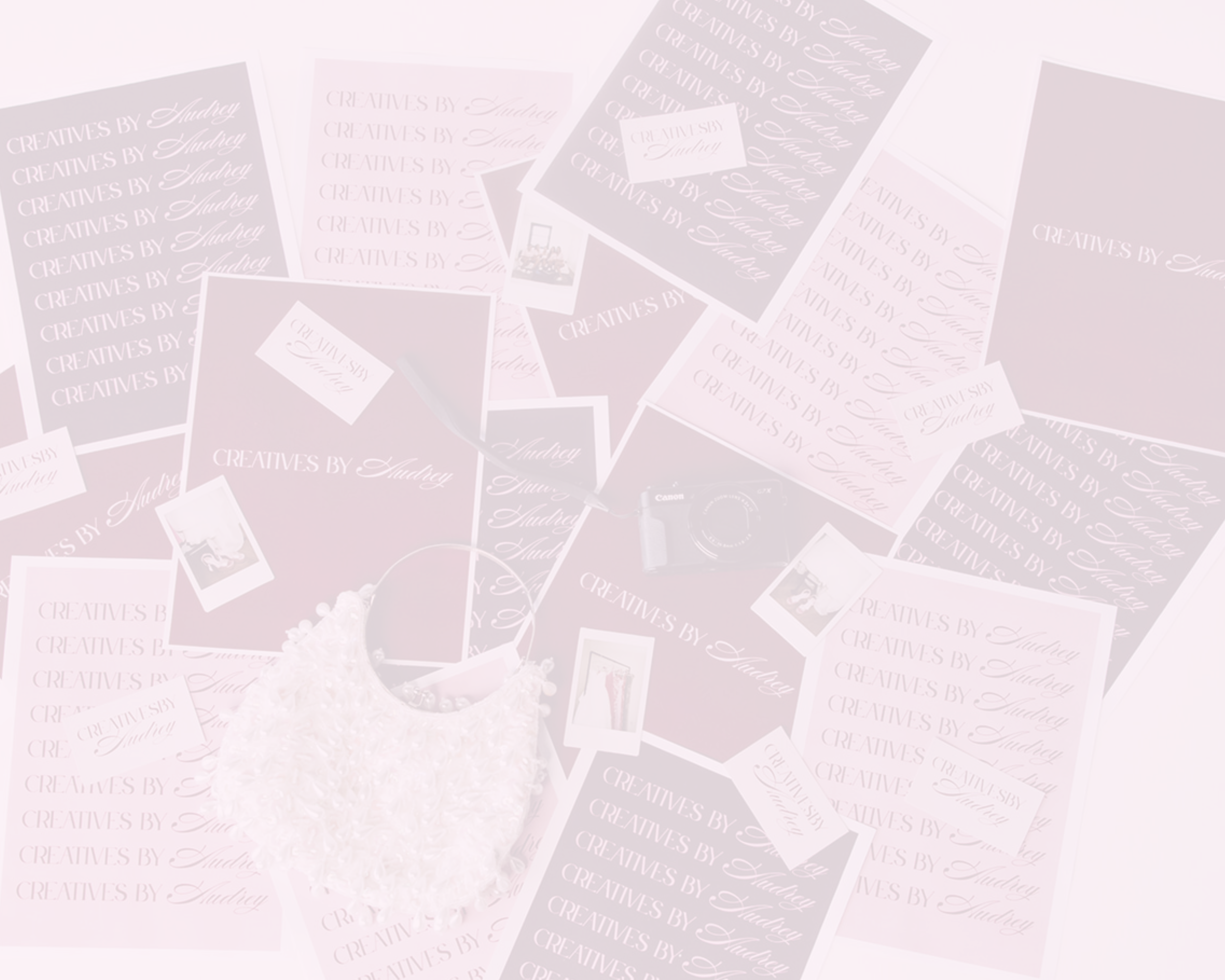 Multiple pink and white cards and photographs scattered on a white surface, with a white pom-pom bag and a small camera among them.