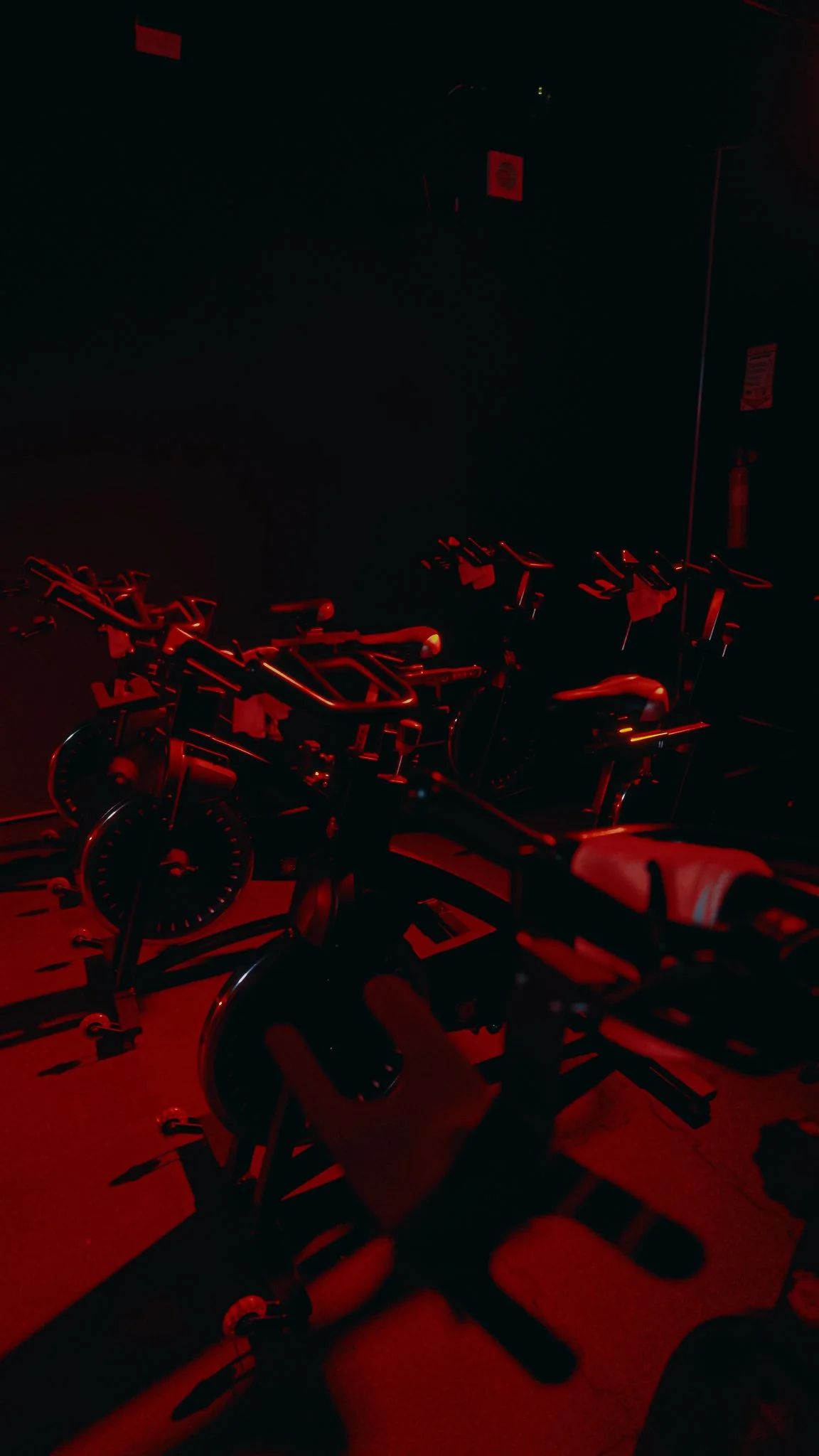 Sucursal de gimnasio con bicicletas estáticas en la penumbra iluminadas con una luz roja
