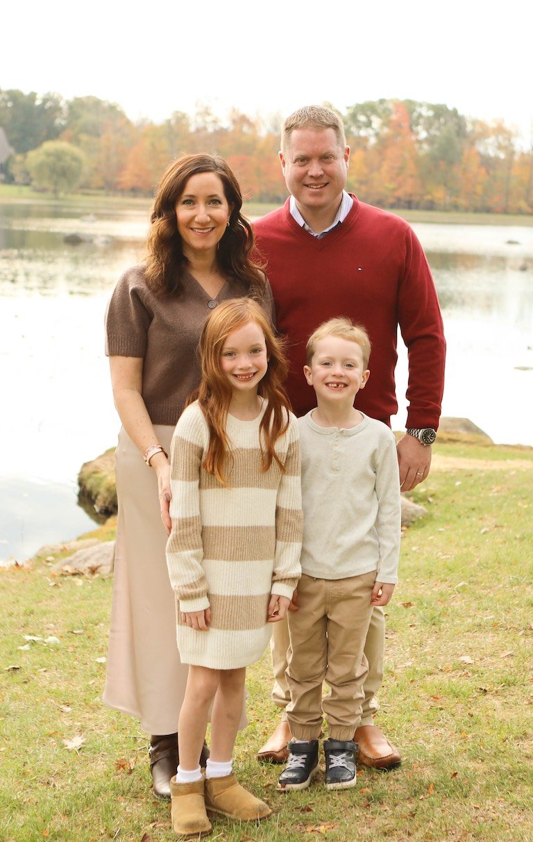 A family of four standing in front of a lake