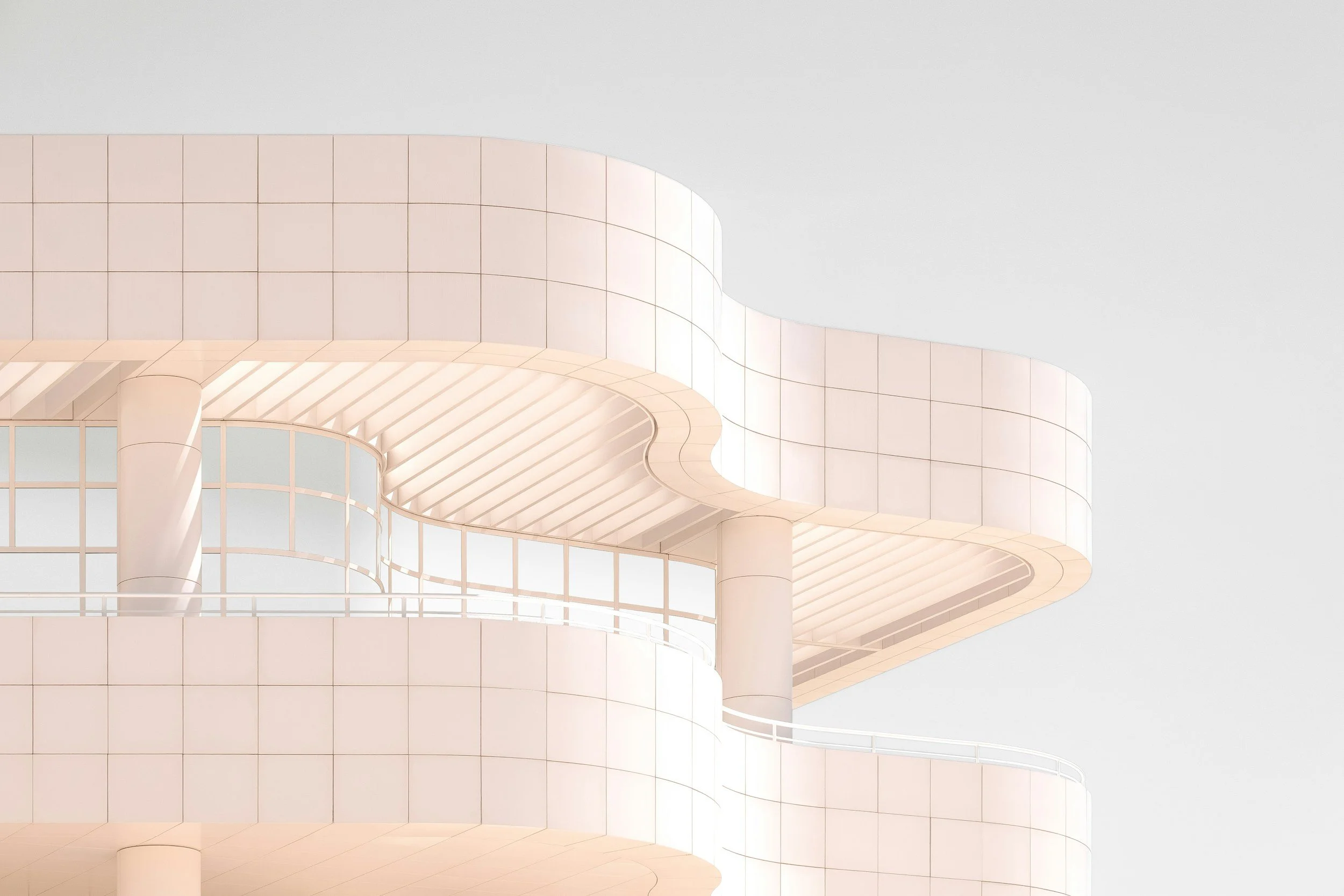 A modern multi-story building with a glass facade at street level, illuminated windows, and surrounded by trees, parked cars, and benches, set against a darkening evening sky.