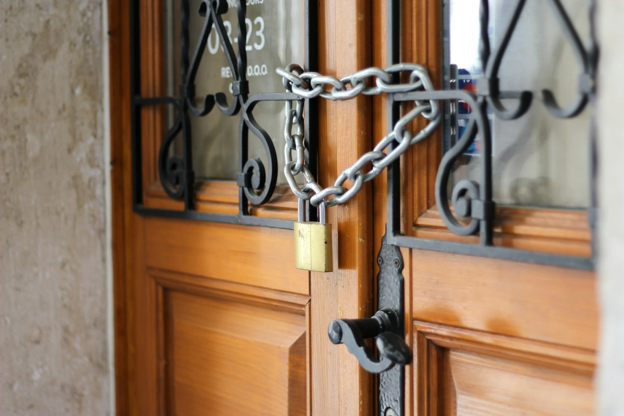 A wooden window with iron bars and a padlock securing it, with some chains wrapped around the bars.