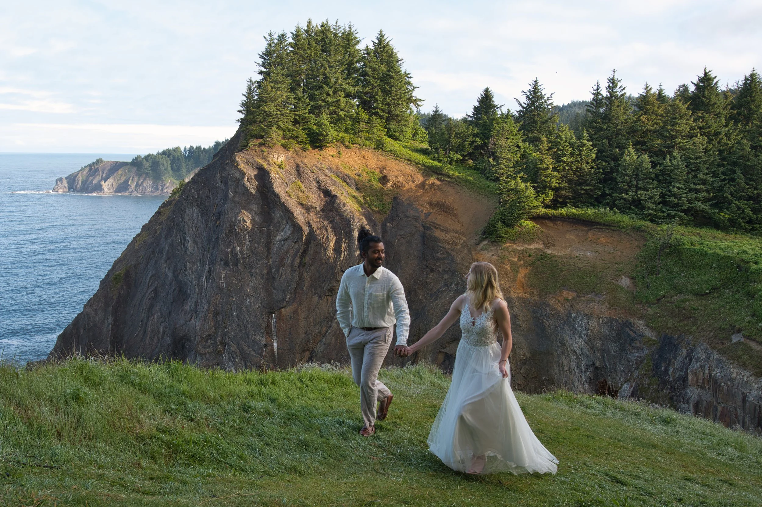 Couple running along the cliffs at Devil’s Cauldron on the Oregon Coast during an intimate elopement.