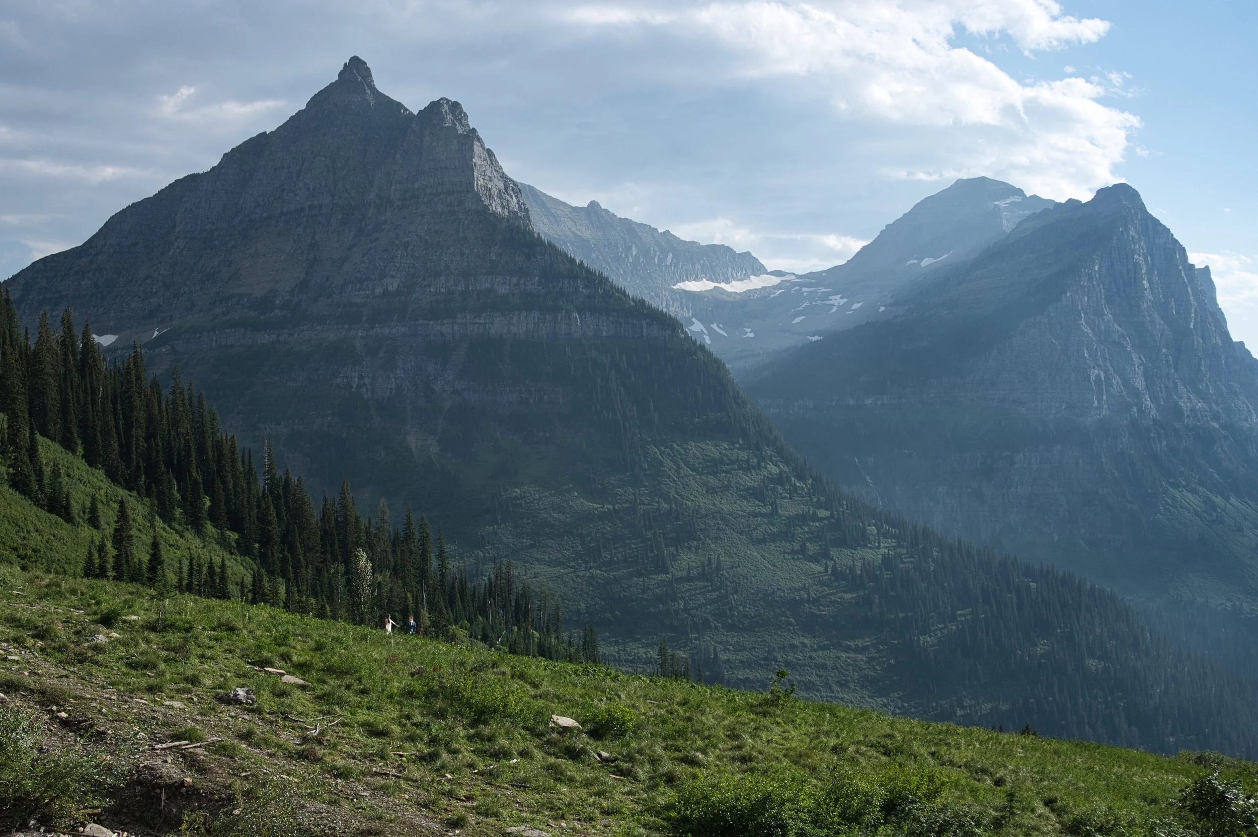 Mountain range with green forested slopes and a clear sky.