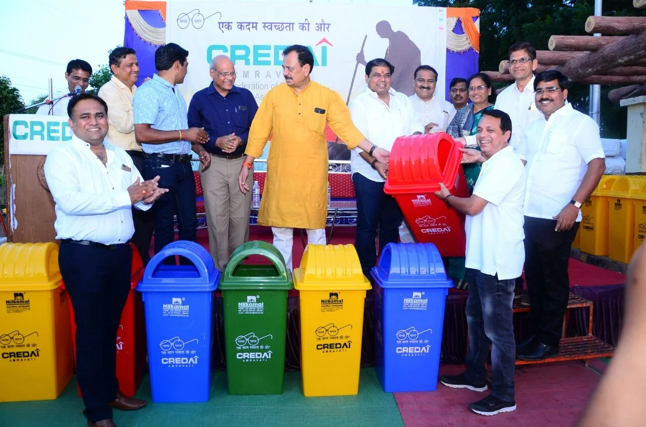 Group of people at a public event unveiling new colored waste bins for recycling.