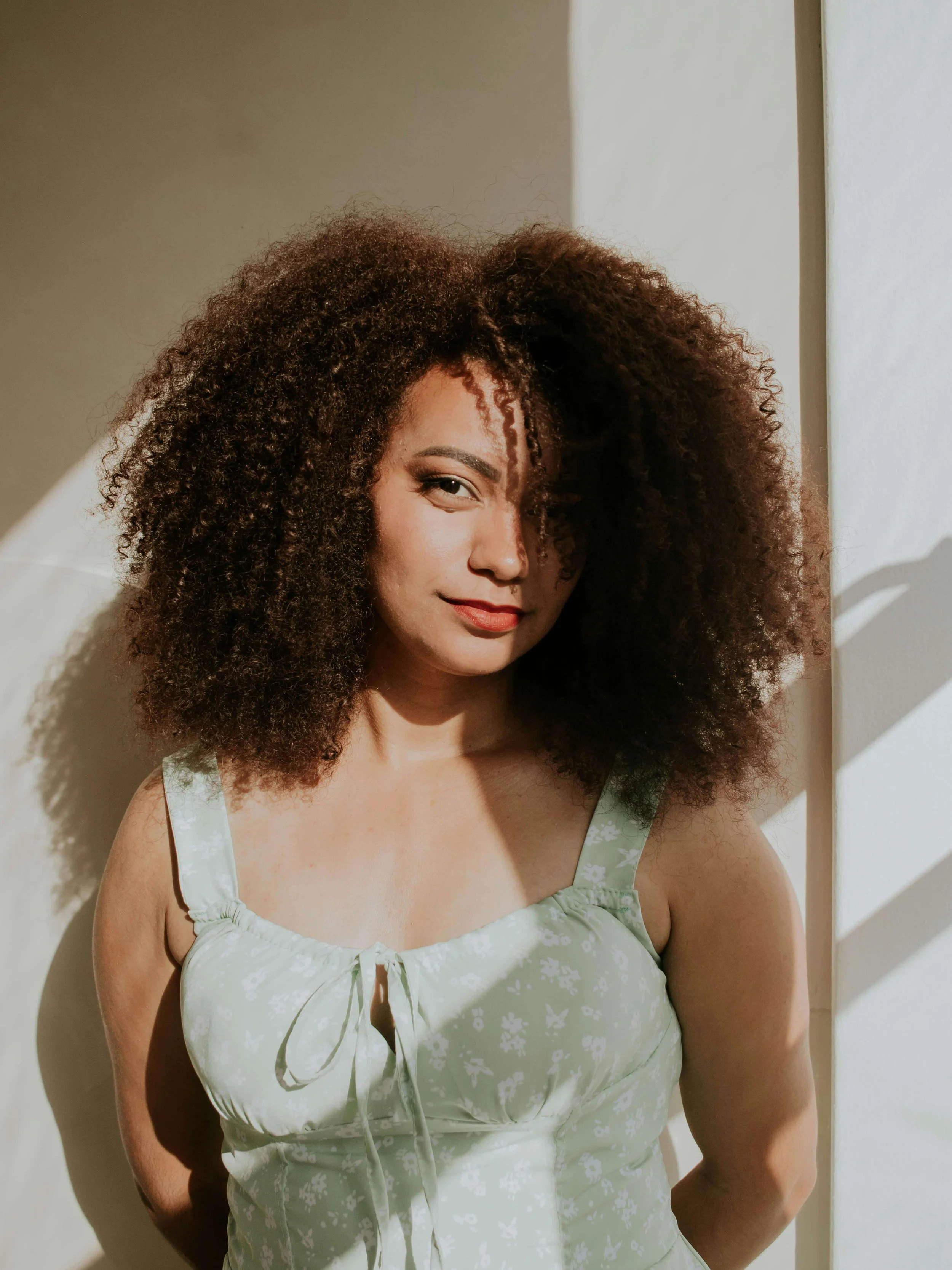 A beautiful Black woman wearing a green dress subtly smiling. Representing how an eating disorder therapist in Raleigh, NC can help you love & feel safe in your body. Contact me today to begin!