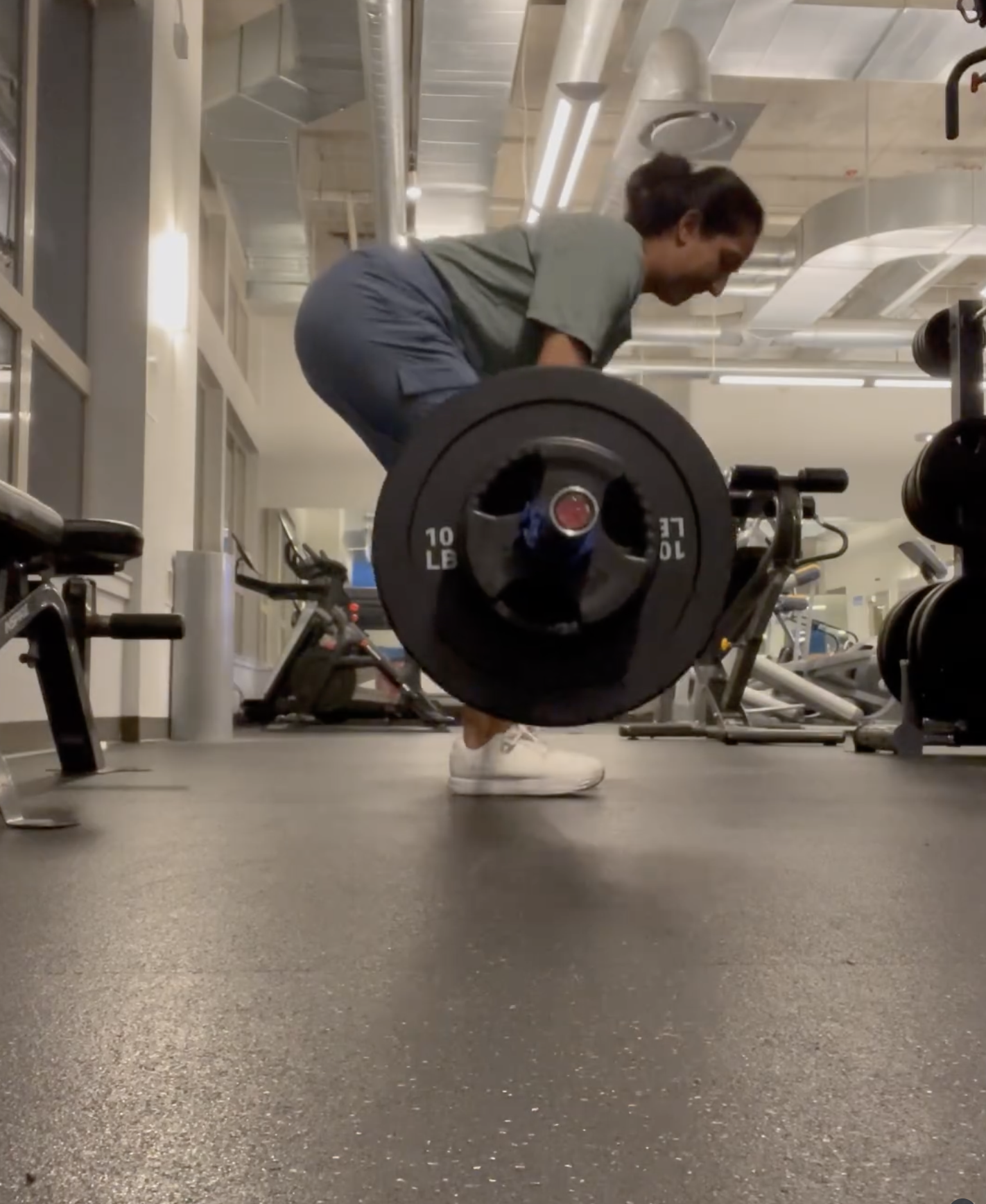 Woman lifting a barbell in a gym.