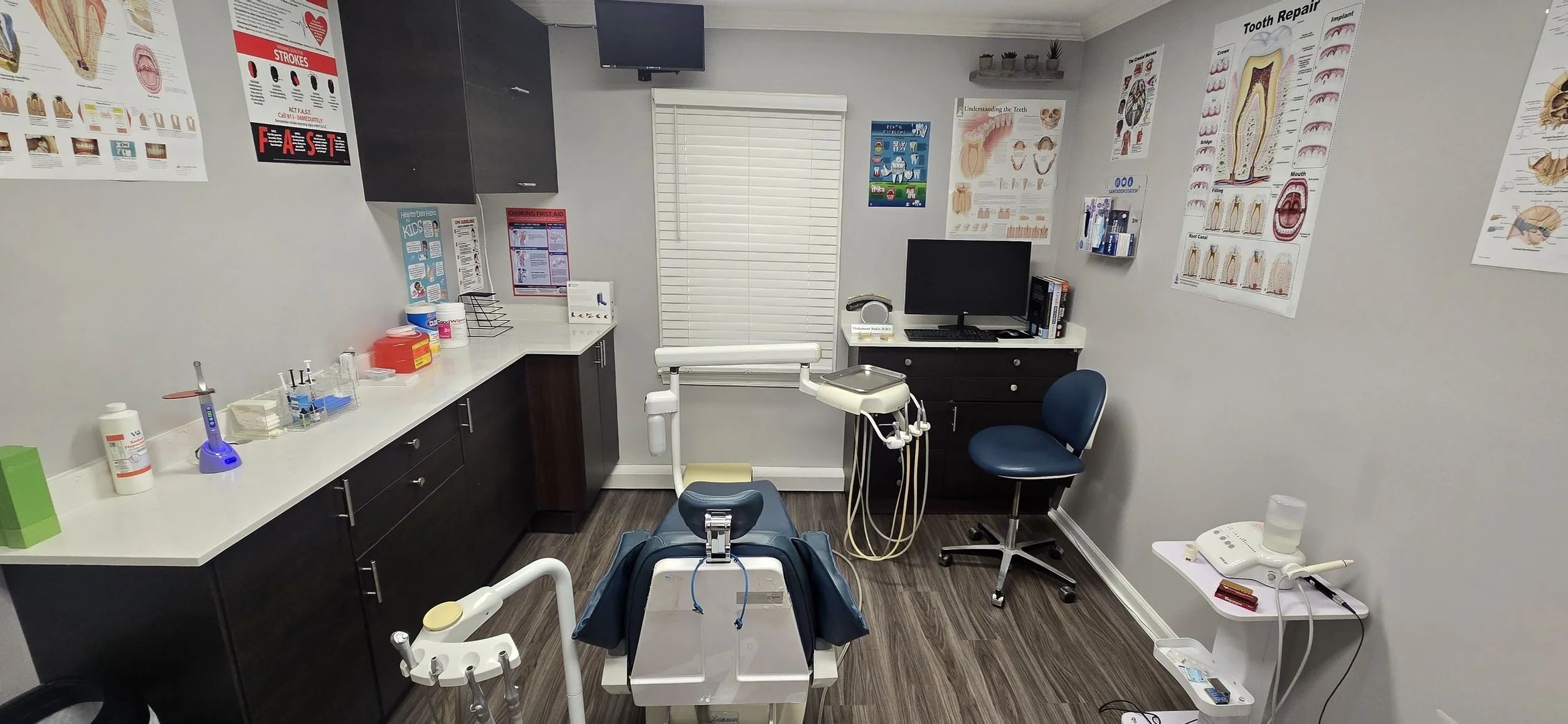 dentist exam room and dentist chair, inside dentist office.  The image has dental posters on the wall and dental equipment.