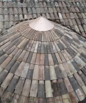 Close-up of a tiled roof with curved clay or ceramic tiles arranged in a circular pattern.