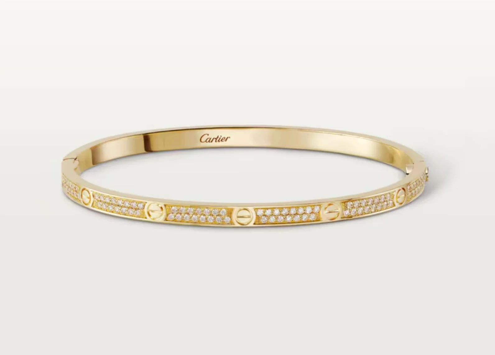 A gold Cartier bracelet with embedded diamonds and screw motif design, displayed on a white background.