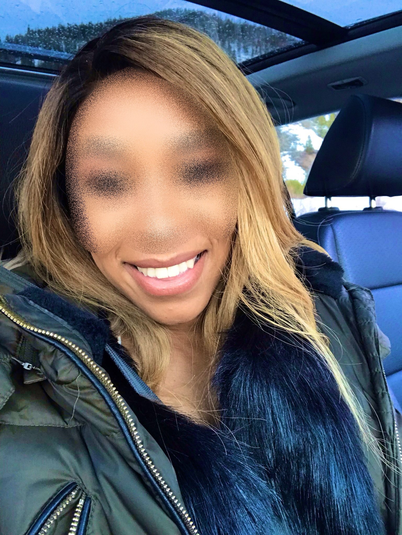 Smiling woman with blonde hair taking a selfie inside a car