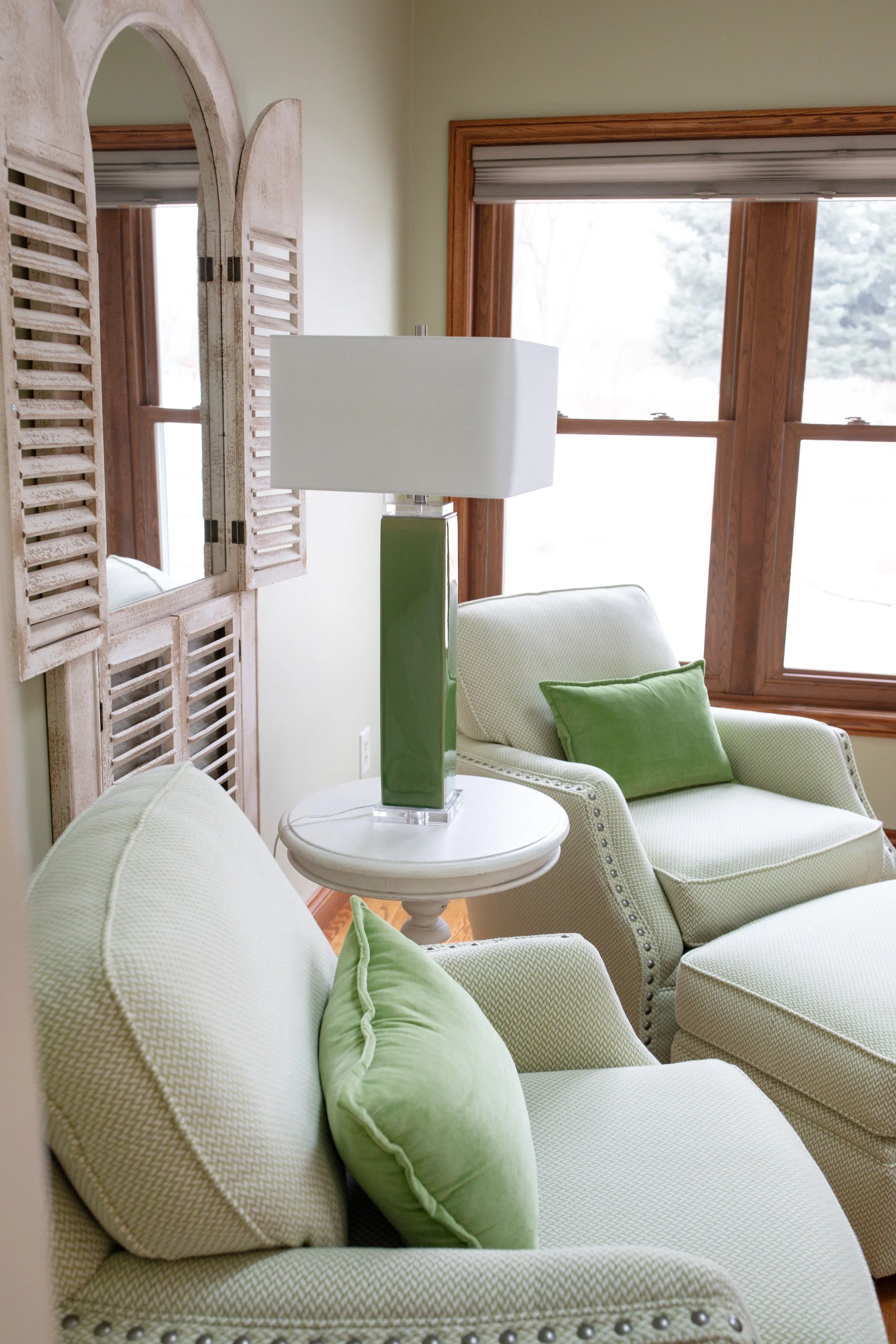 Comfortable seating area with custom upholstered chairs, soft green accents, and natural light, creating a calm, inviting interior for lakeside living in Southwest Michigan.