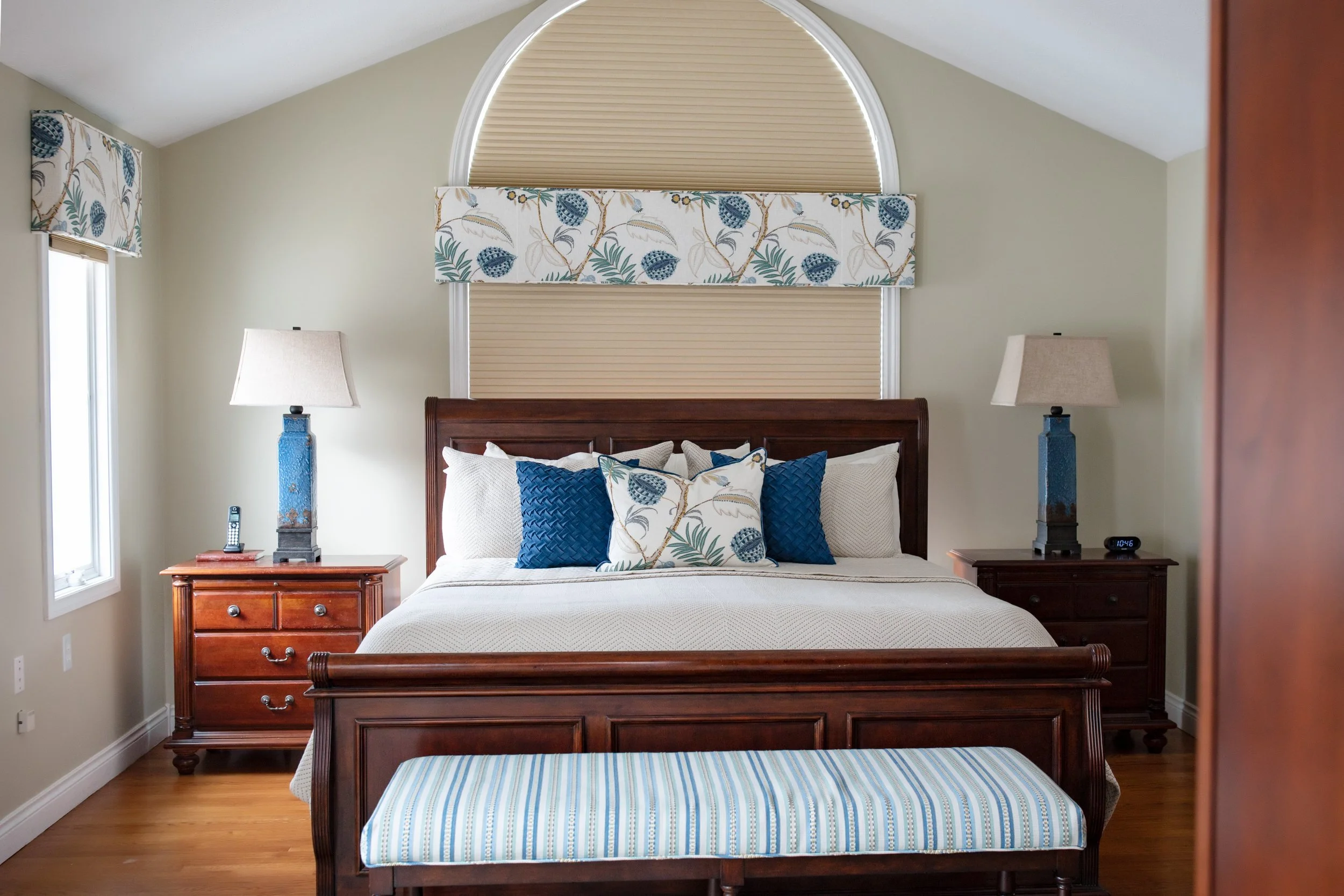 Primary bedroom interior design with custom bedding, tailored window treatments, and warm wood furniture, creating a calm, comfortable retreat for lakeside living in Southwest Michigan.