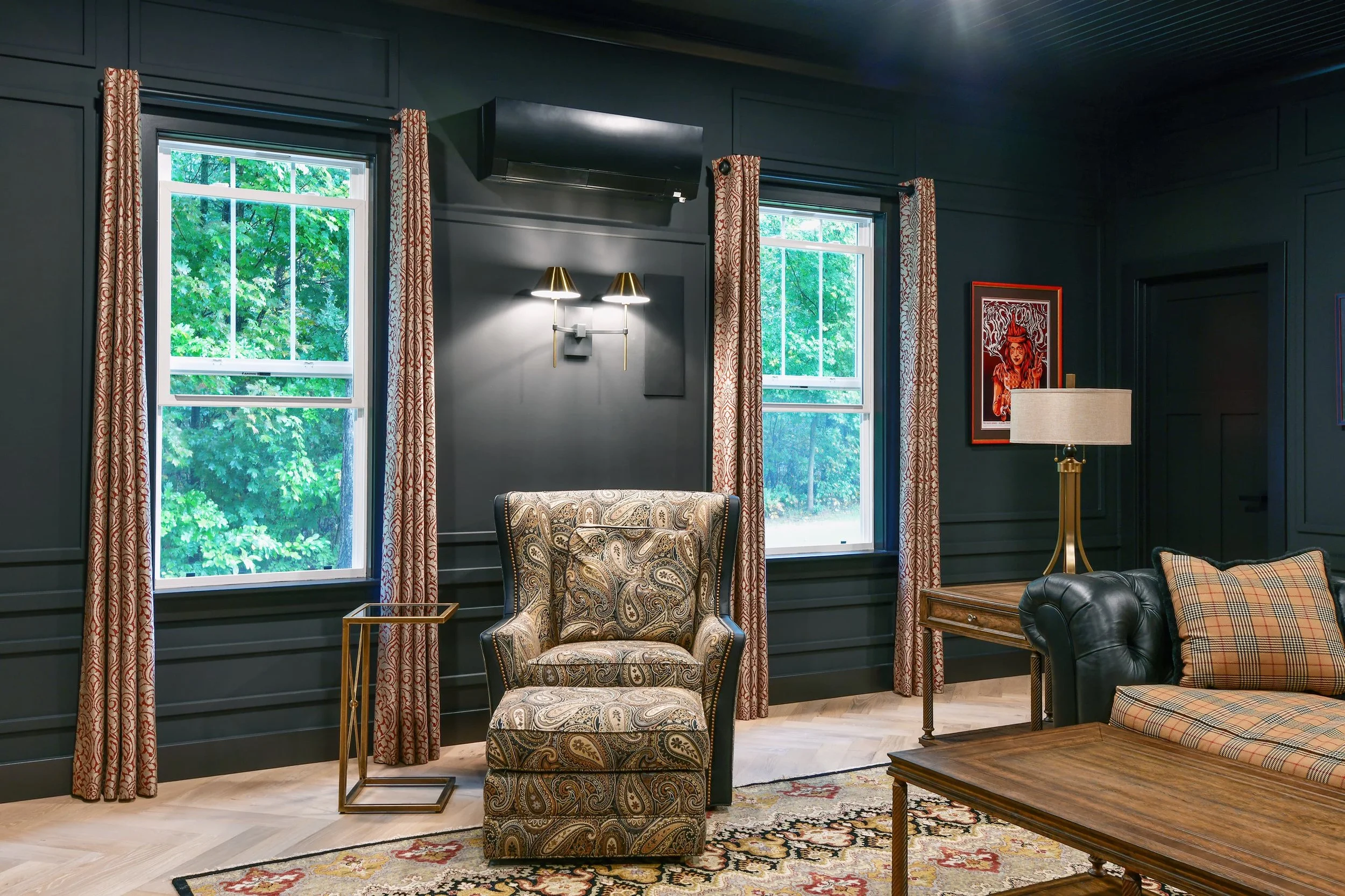 Accent seating area with custom window treatments, layered lighting, and rich textures, adding warmth and character to a dark, sophisticated interior design.