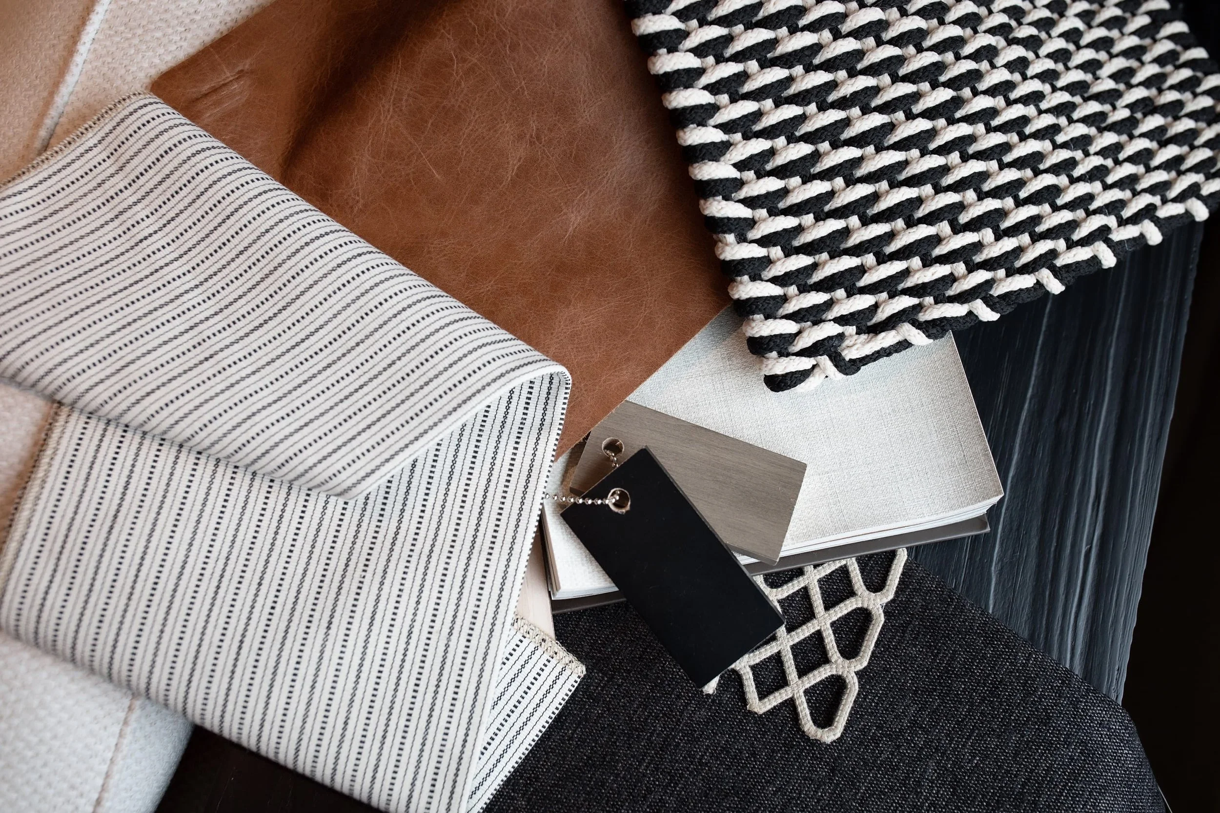 Collection of fabric samples, a notebook, and a keychain with a black tag on a table.