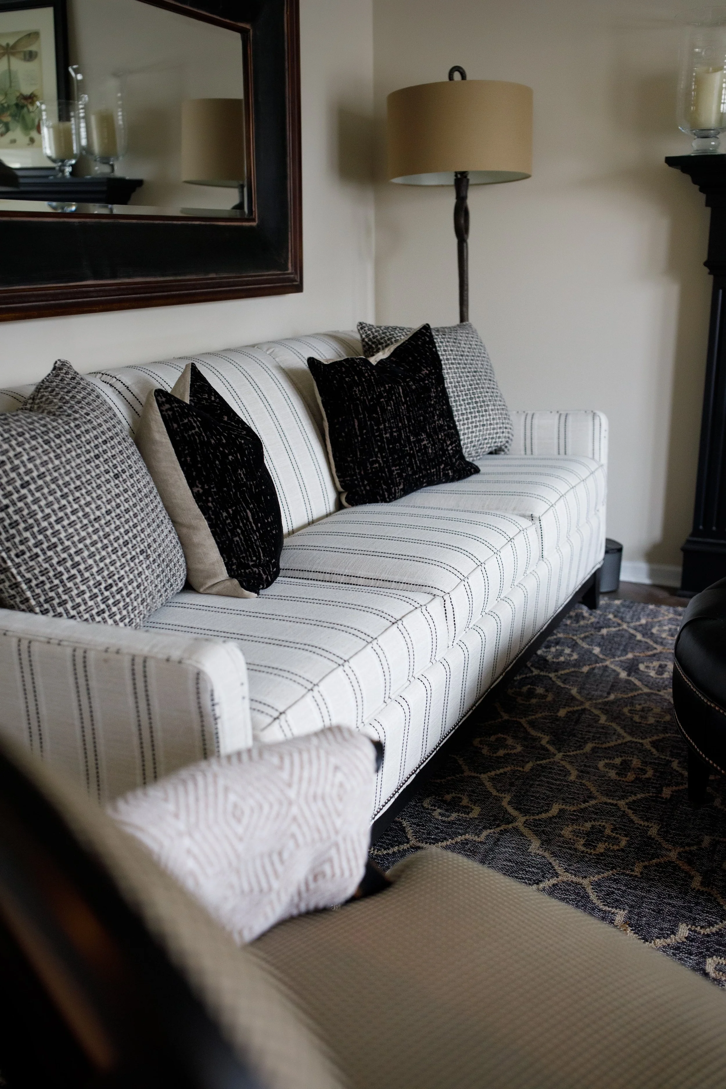 Living room interior design featuring a custom upholstered sofa, layered neutral pillows, and warm lighting, creating a comfortable, inviting gathering space in a Southwest Michigan home.