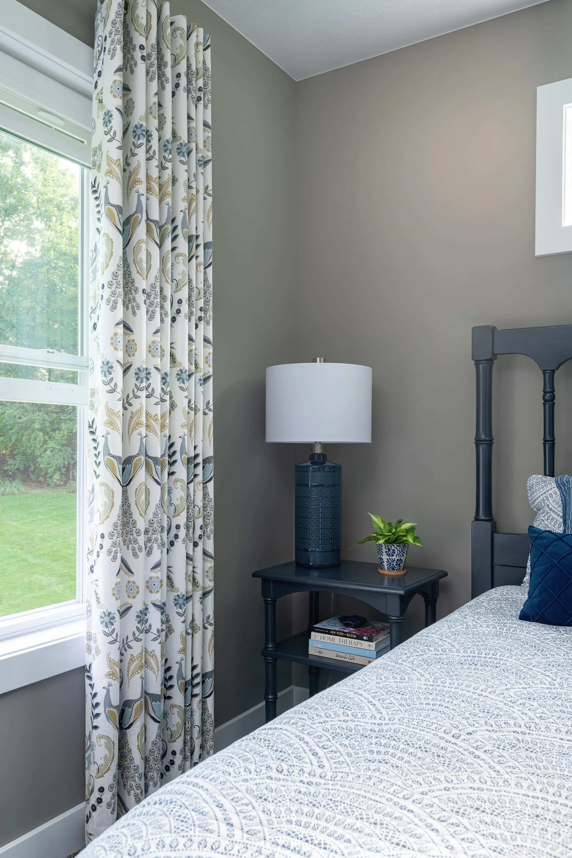 Bedroom interior design with custom window treatments, soft neutral walls, and layered bedding, creating a calm, comfortable retreat in a Southwest Michigan home.