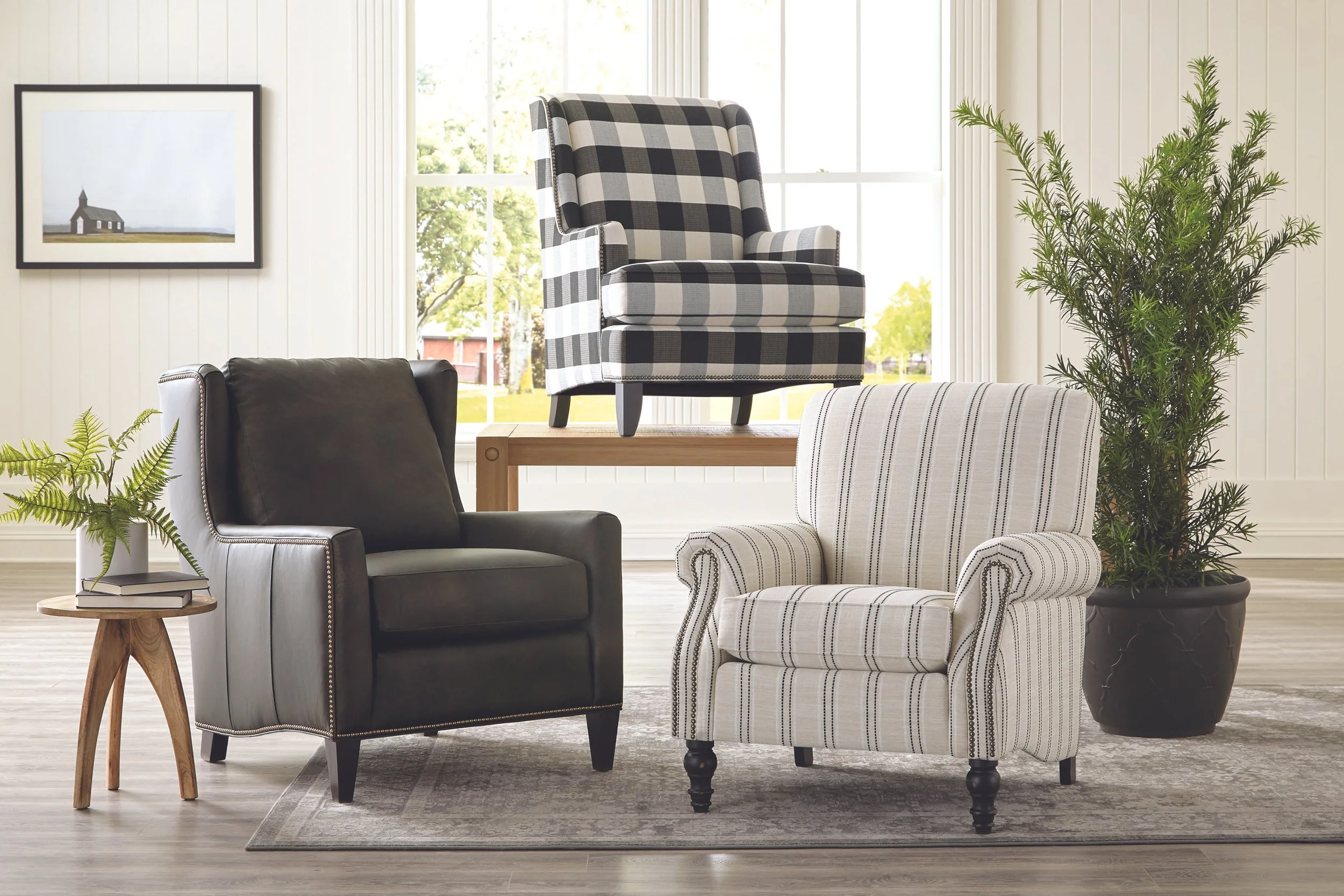 A showroom display of five different armchairs and several rolled-up fabric samples in the background.