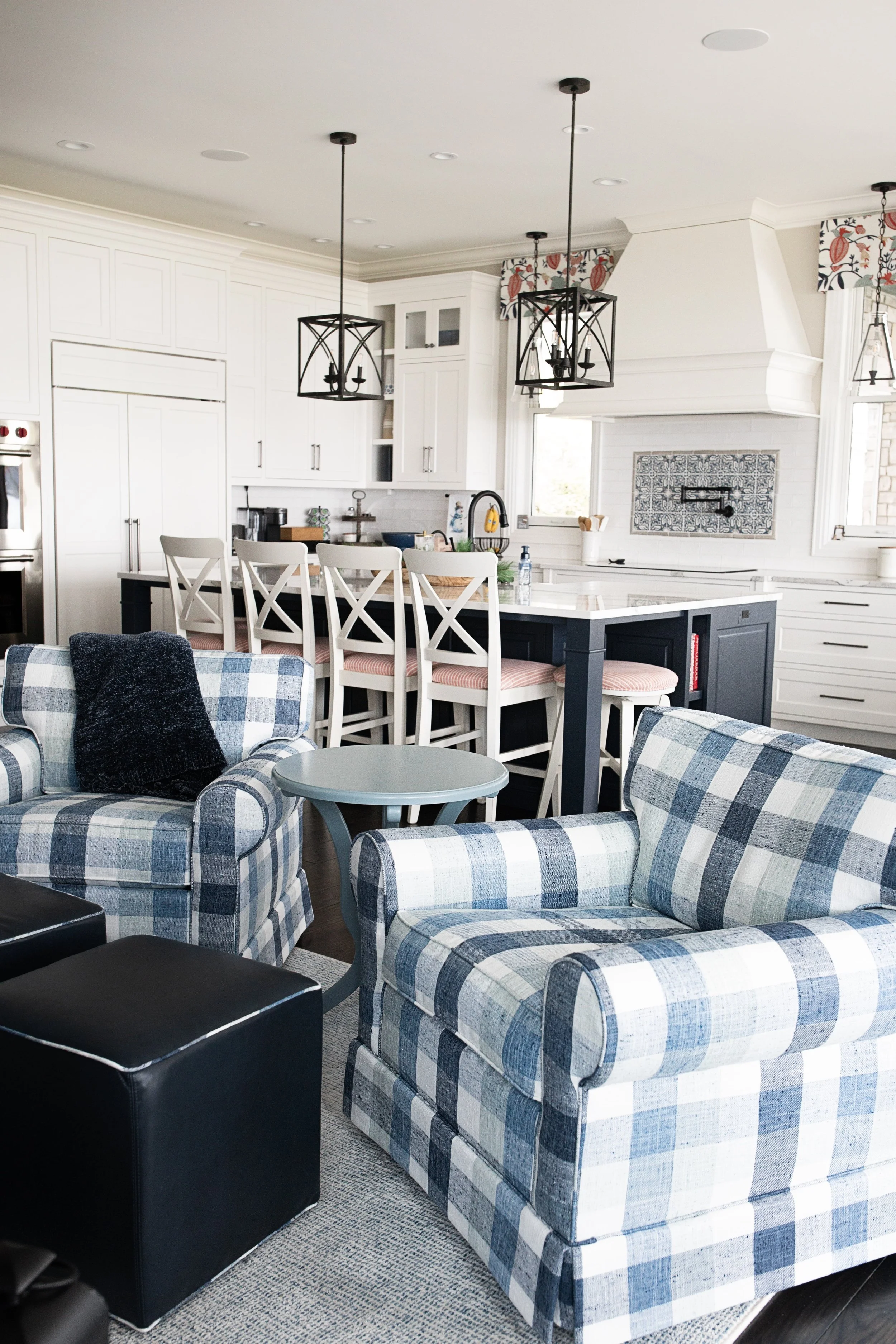 Open-concept kitchen and living area with custom interior design, featuring a navy kitchen island, white cabinetry, and coordinated seating for a warm, welcoming lakeside home in Kalamazoo, Michigan.