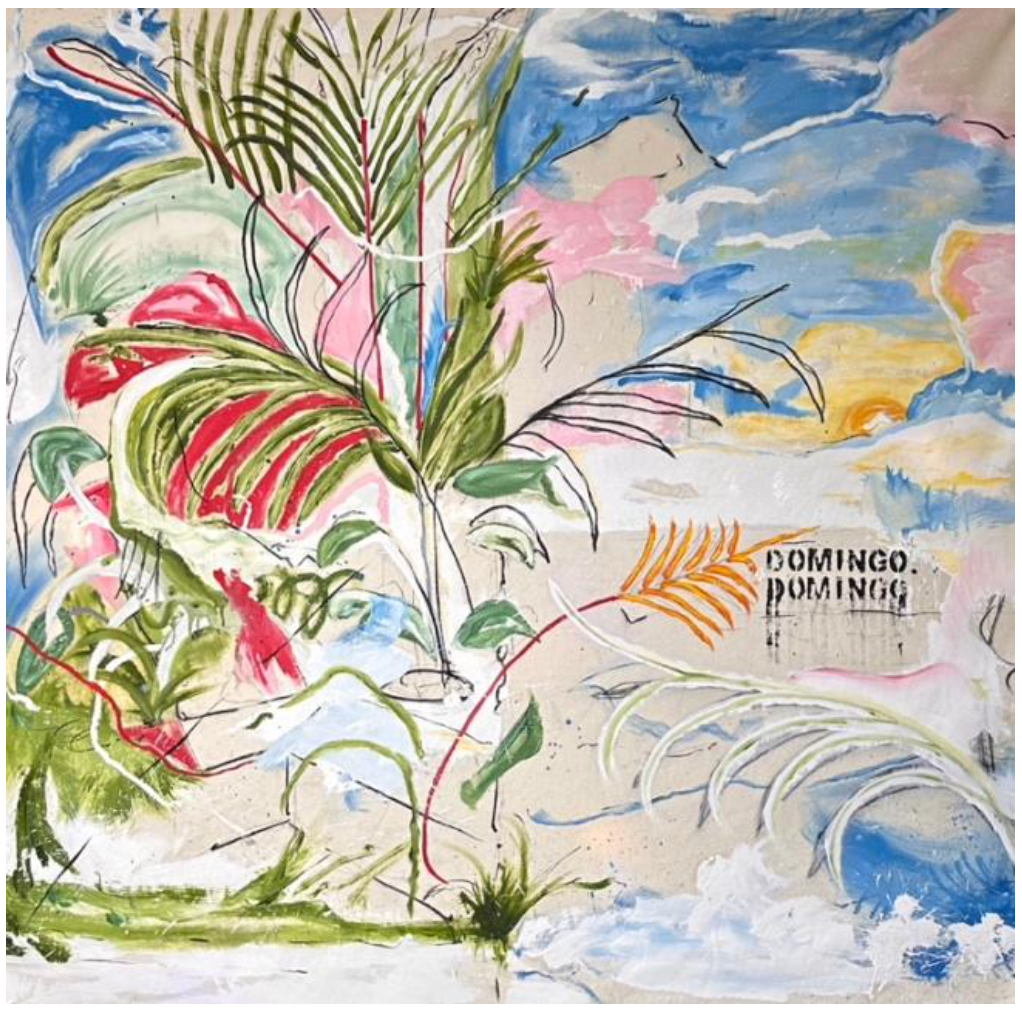 A man with glasses sitting in a chair in front of a large colorful abstract mural featuring sketchy faces, hands, and various shapes.