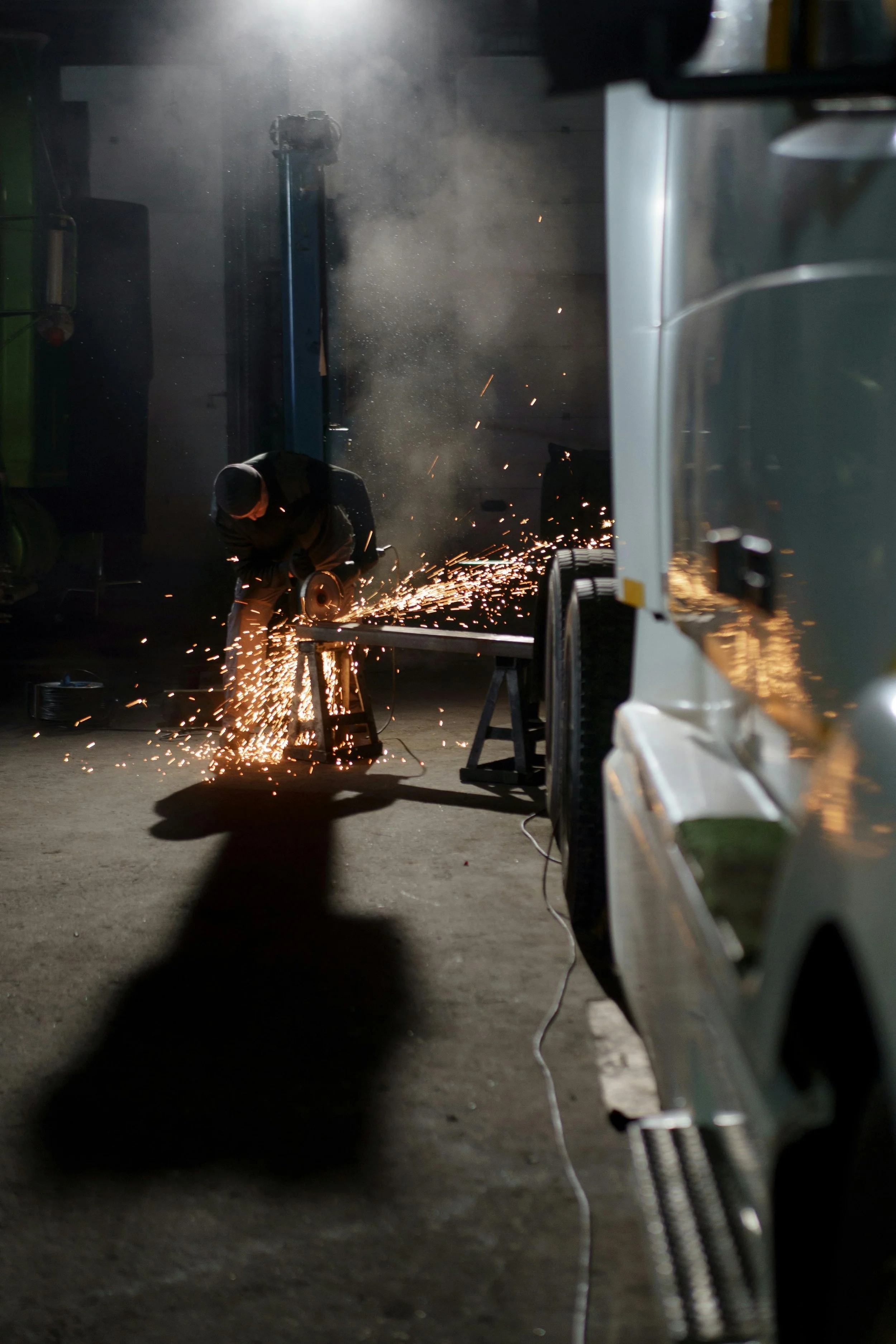 A person welding metal inside a workshop with sparks flying.