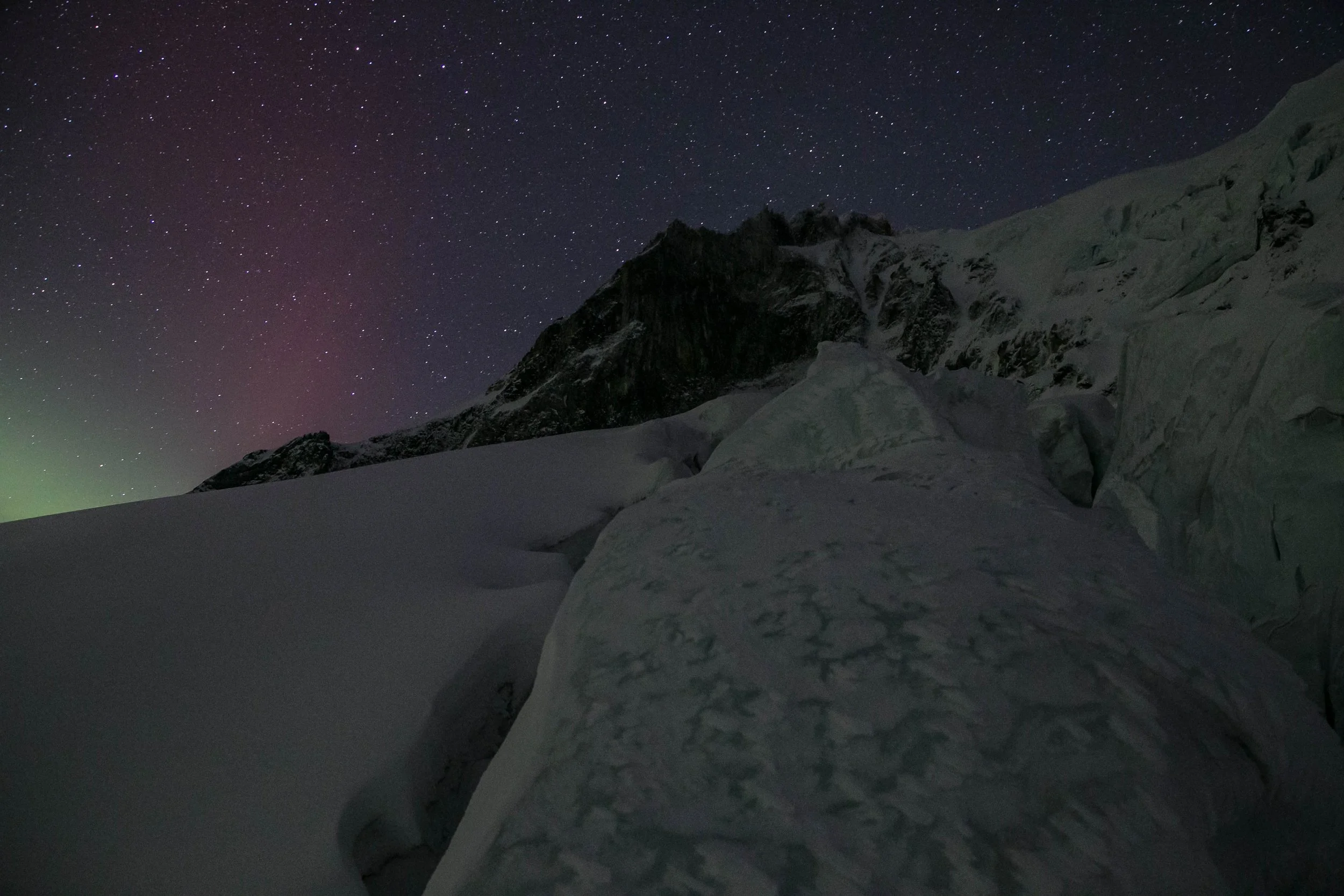 Night sky filled with stars over snow-covered mountain landscape.