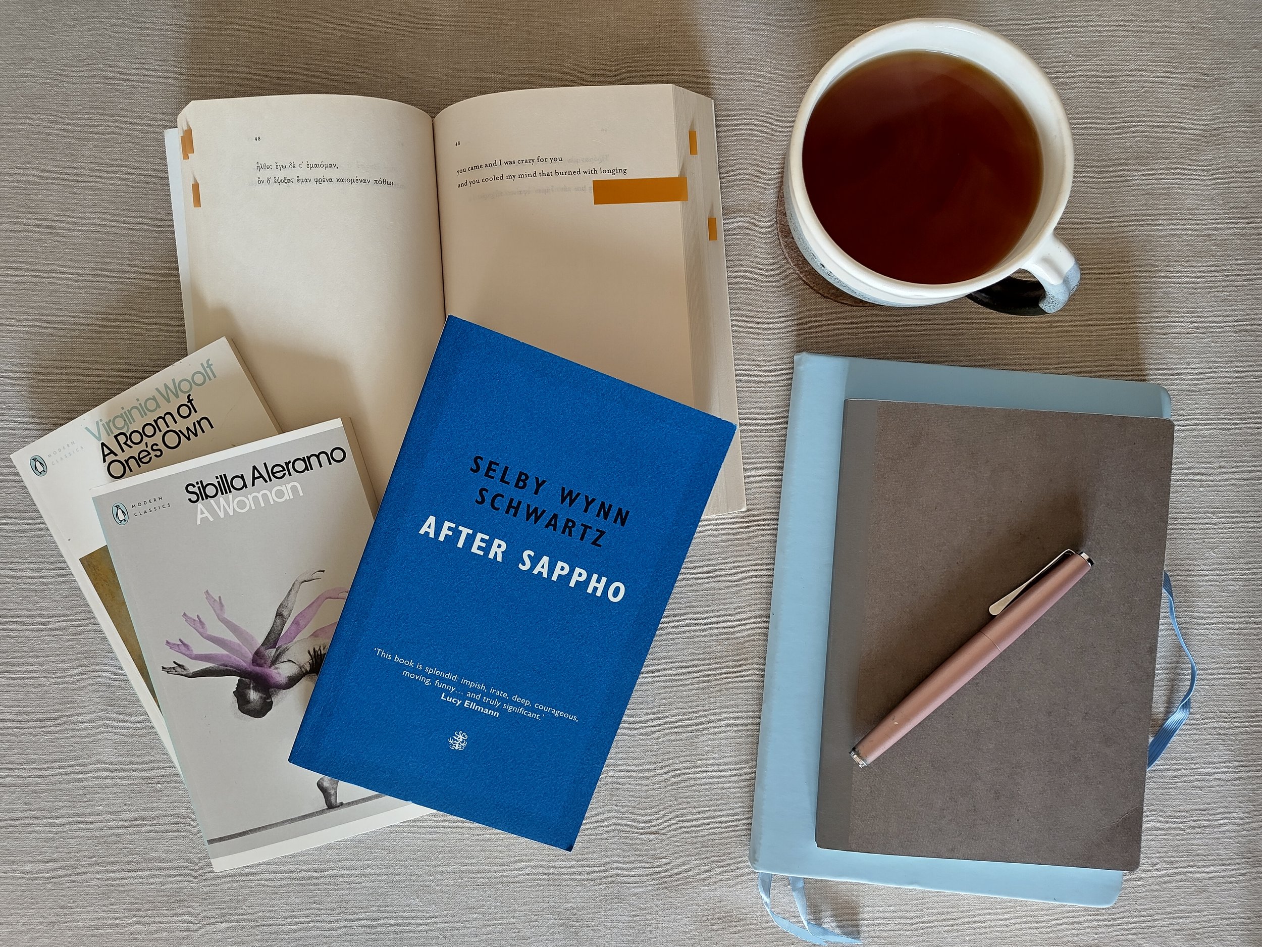 pile of books and notebooks with fountain pen and tea