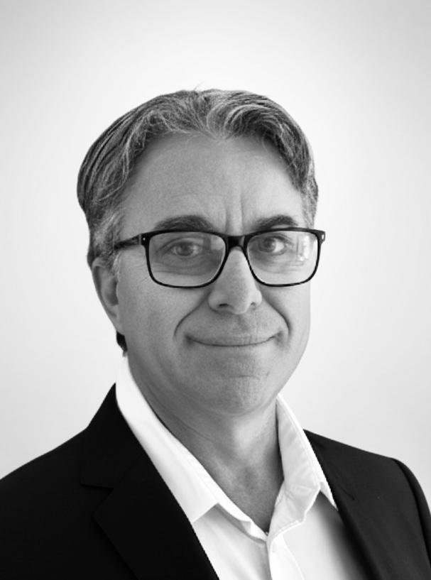 Black and white portrait of a man with glasses, smiling, wearing a suit and white shirt.