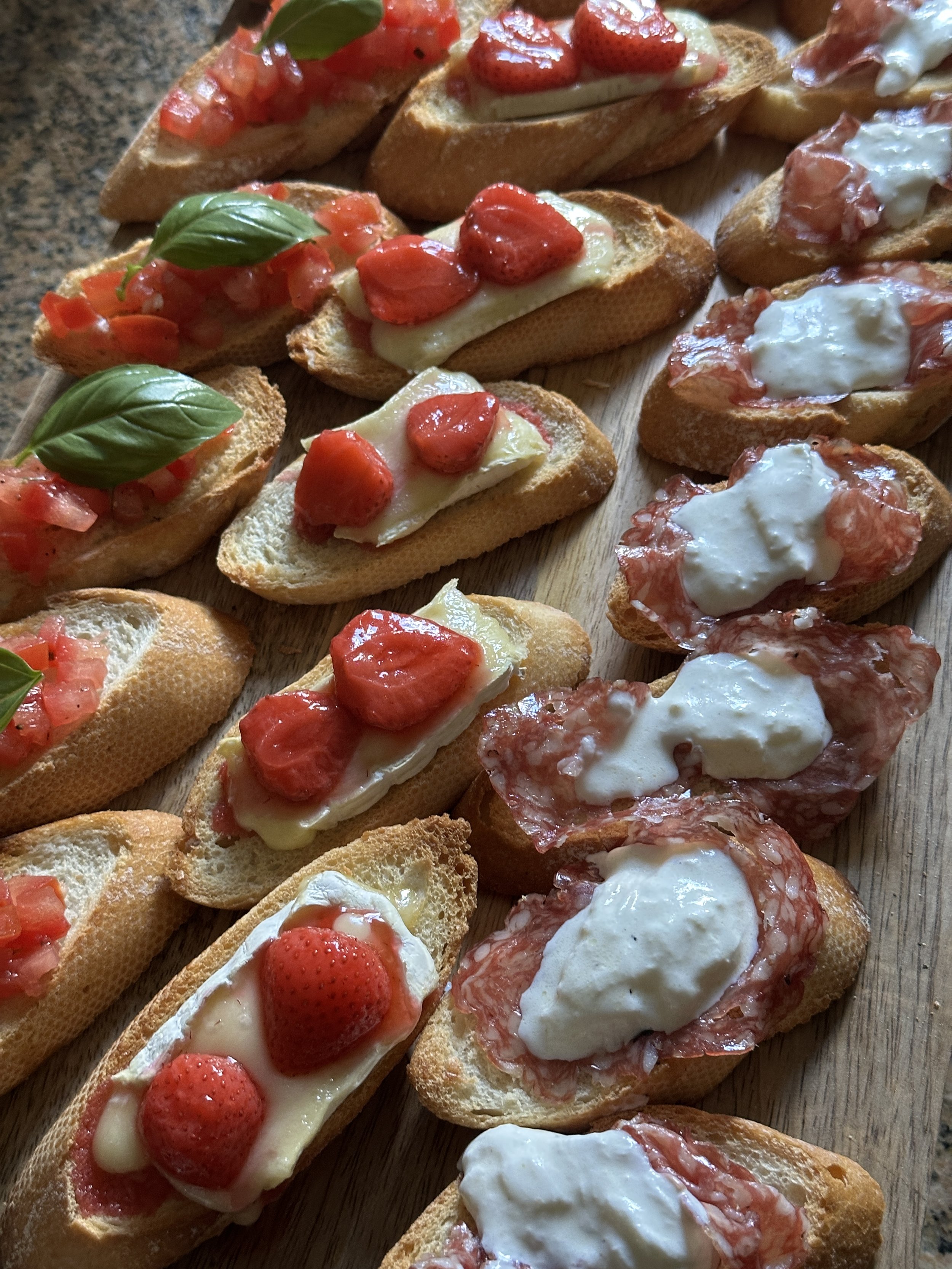 Mini Italiaanse bruschetta met tomaat, mozzarella, basilicum en salami op houten snijplank.