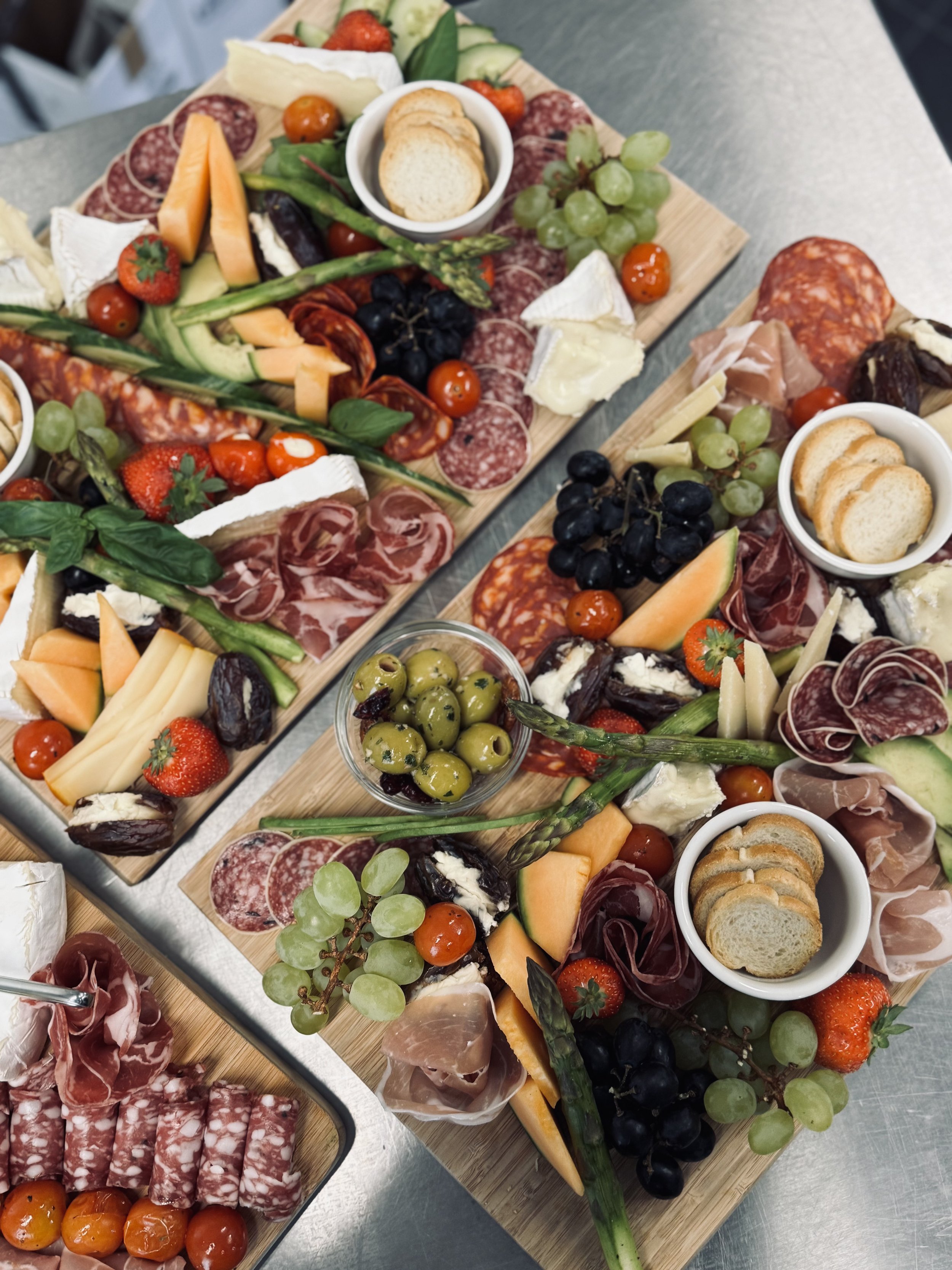 Decoratief geperst vleeswaren en kaasplanken met druiven, aardbeien, cherrytomaten, asperges, crackers, en vers fruit.