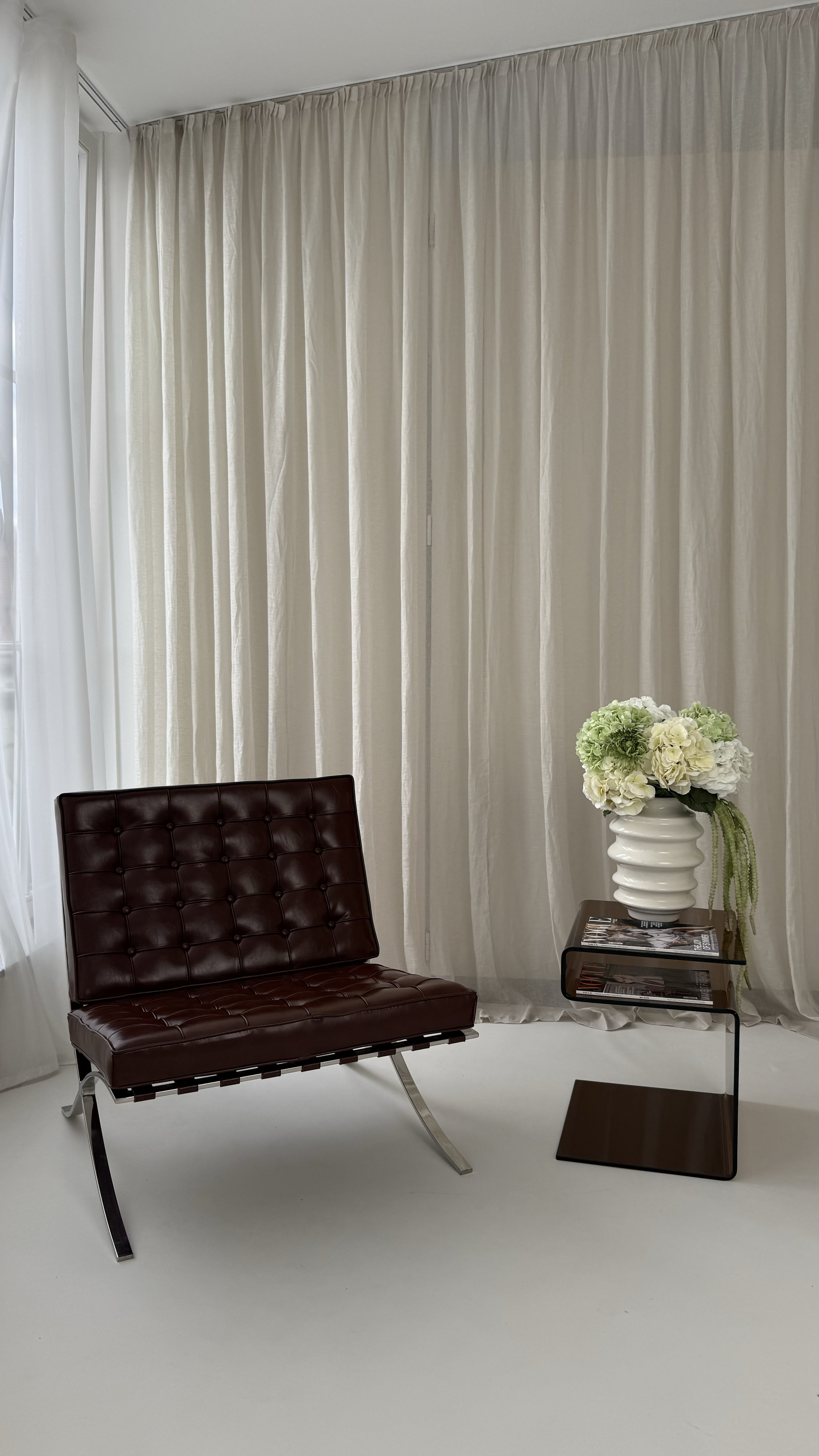 Tageslichtstudio wild:studios in Stuttgart mit Leinenvorhängen, braunem Ledersessel und Blumenarrangement