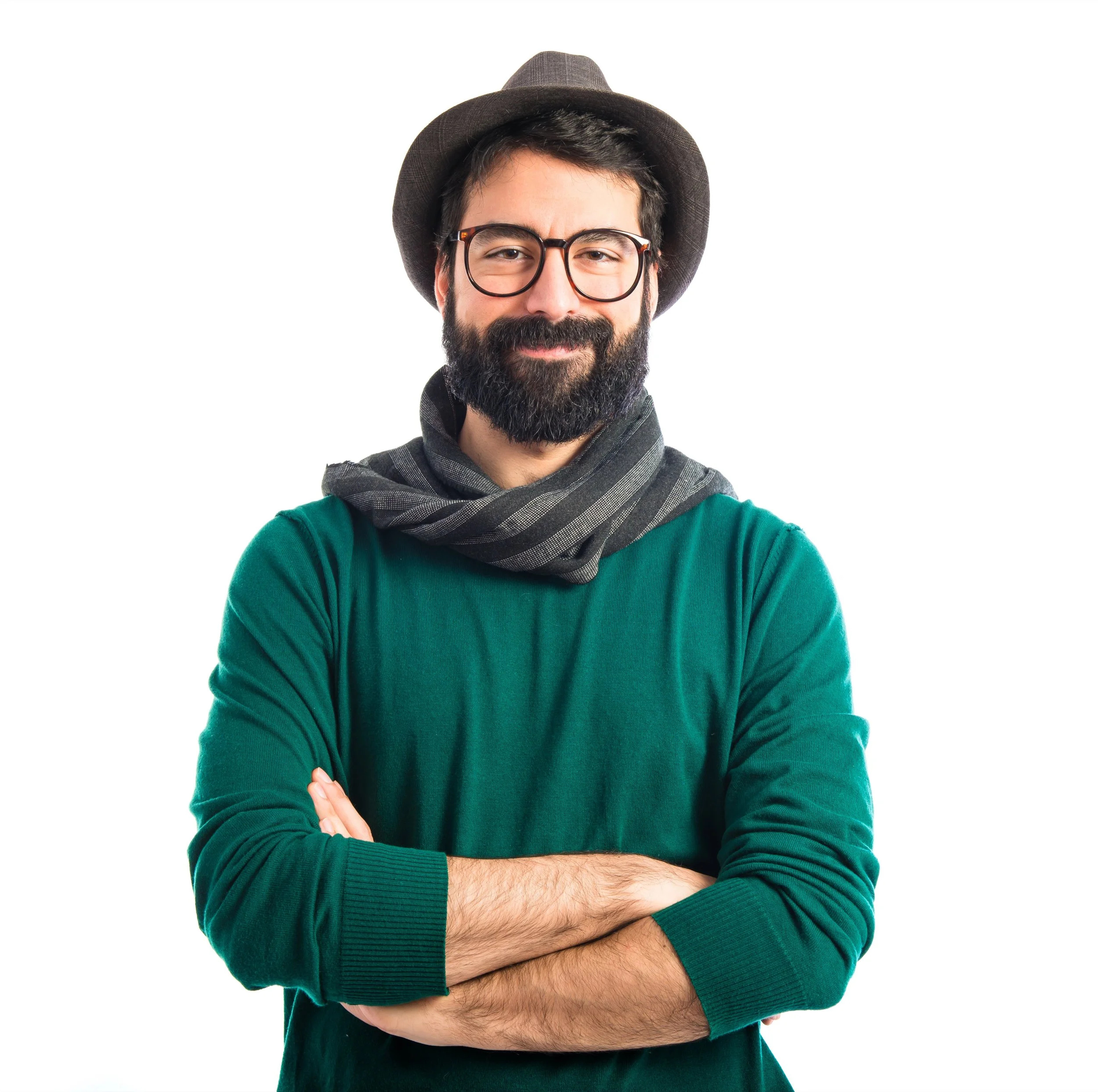 A man with a beard and glasses is smiling, wearing a hat, scarf, and a green long-sleeved shirt, with arms crossed against a white background.