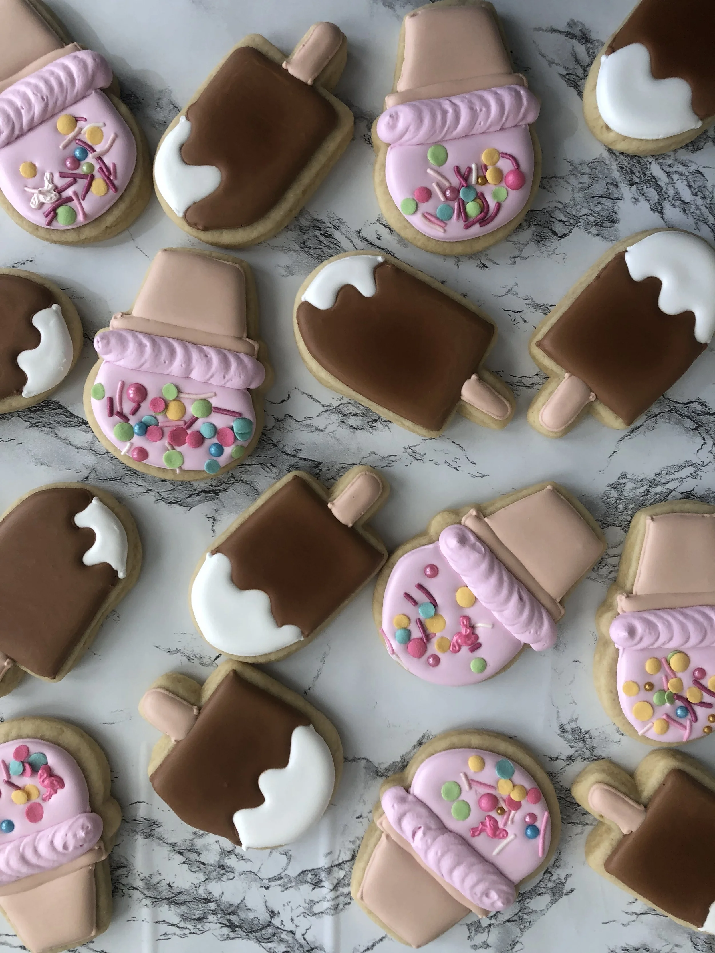 Sugar cookies decorated as pink ice cream cones and fudgesicles