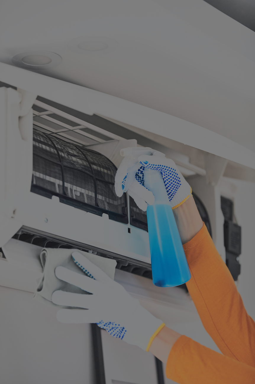 Person cleaning an air conditioning filter with a spray bottle.