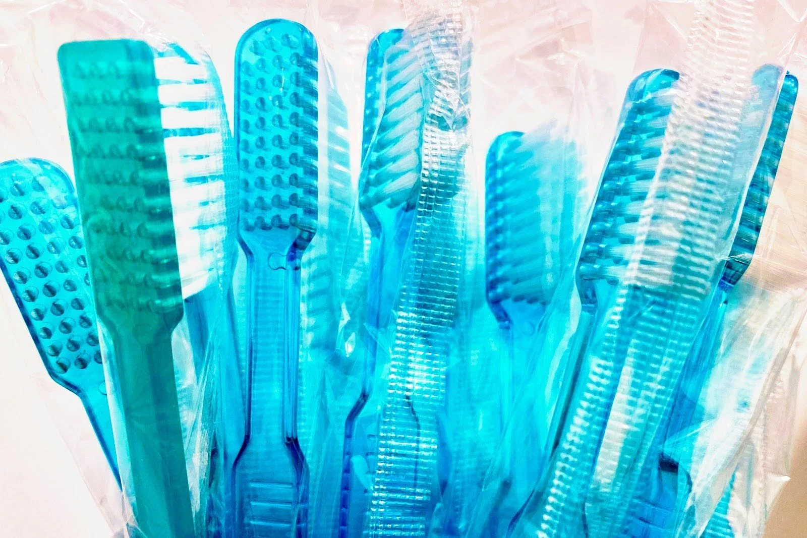 A collection of standard plastic toothbrushes individually wrapped in plastic